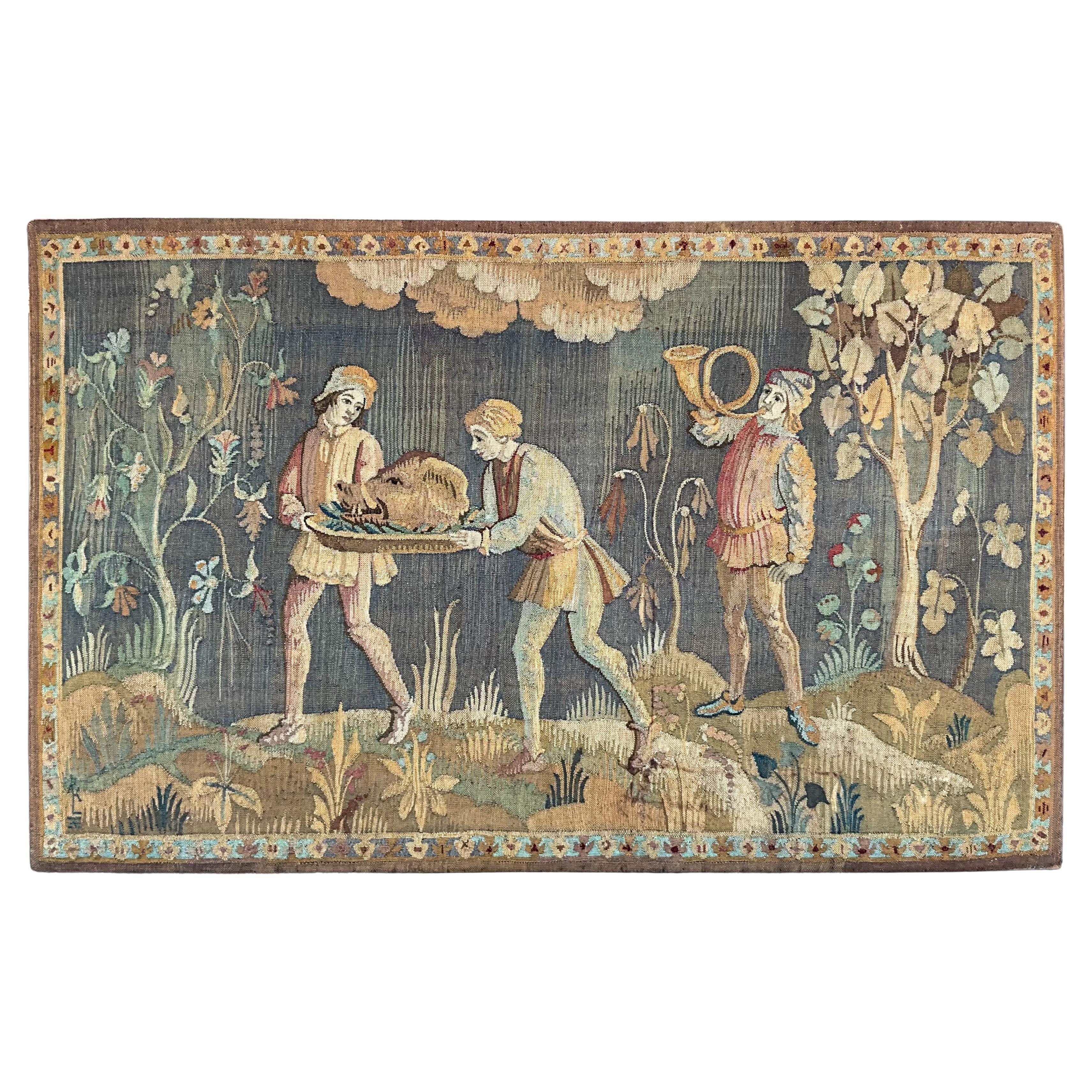 This is a 19th century continental tapestry depicting the Boar’s head feast. The tapestry is mounted on a large wooden stretcher with hanging wire. The Boar’s Head feast originated in Rome but was adopted by the church in medieval England to