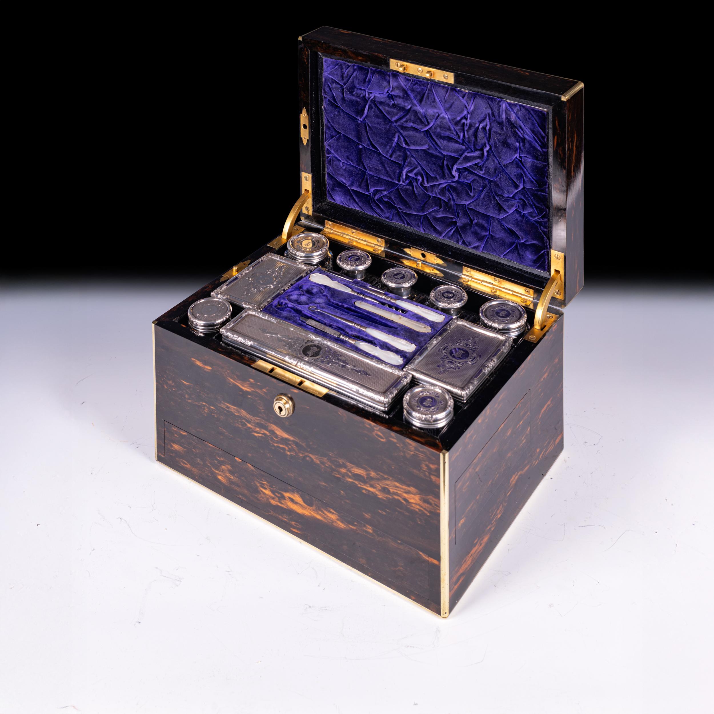 A superb quality ladies’ travelling vanity case, veneered in richly figured coromandel wood with brass edging and escutcheons, the hinged lid opening to reveal a fitted interior lined in deep royal blue velvet and ruched silk. The upper compartment
