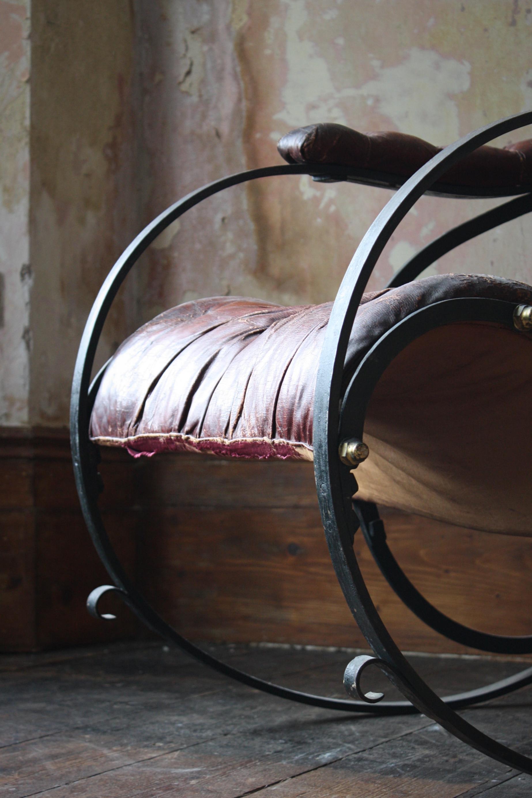 A Victorian cast iron and leather upholstered rocking armchair attributed to R.W.Winfield second half 19th century in age. The original ox blood button upholstered leather seat above the metal frame with gilt brass screw-caps and bent stops, Marks,