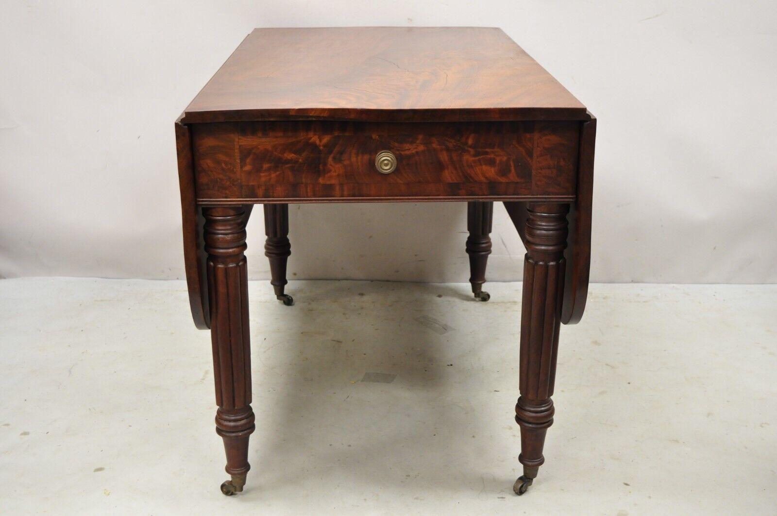 Antique 19th century Crotch Mahogany federal drop leaf breakfast dining table w/ drawer. Item Drop leaf sides, twin carved legs, (1) faux drawer, (1) dovetailed drawer, rolling casters, beautiful wood grain, very nice antique item, quality American
