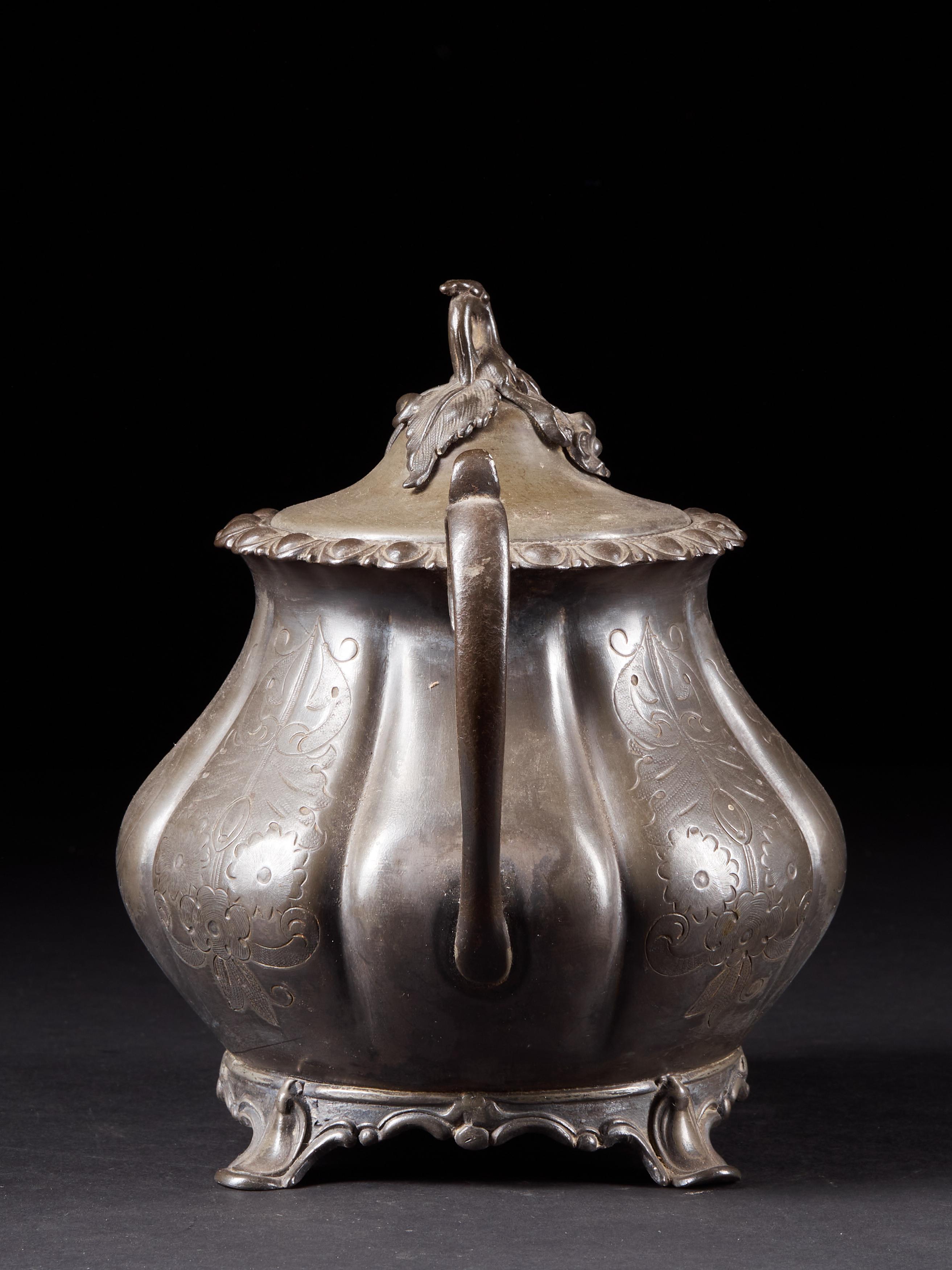 Made of pewter, this cream or sugar pot has a detailed flower bud handle on the lid. It also proudly displays several floral patterns. A lovely antique with a timeless charm showing a nice patina.