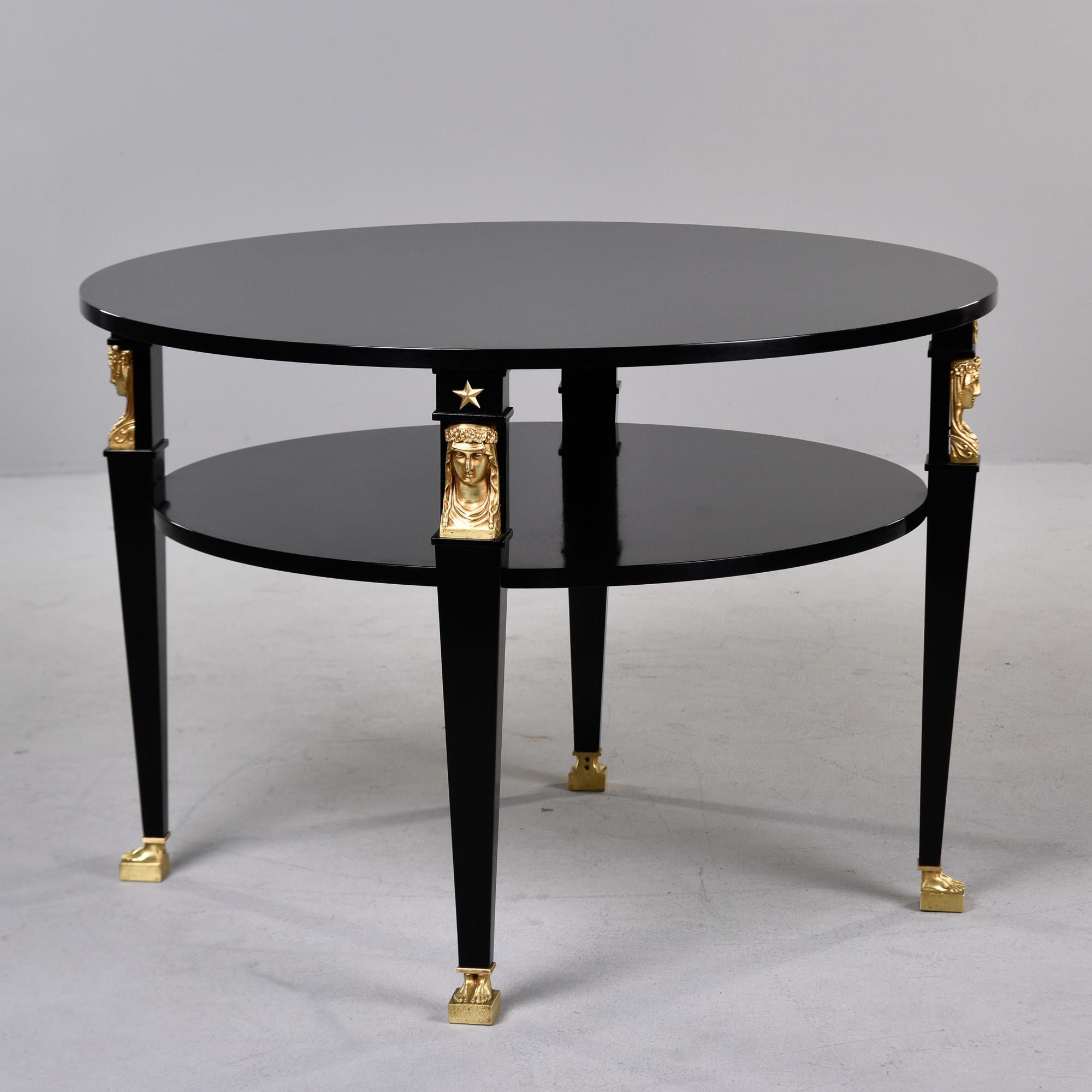 Found in France, this two tier round table has strong empire / neoclassic style elements. We had the table professionally ebonised in England and the gilt finish on the bronze figural mounts was restored as well. Each of the four legs is decorated