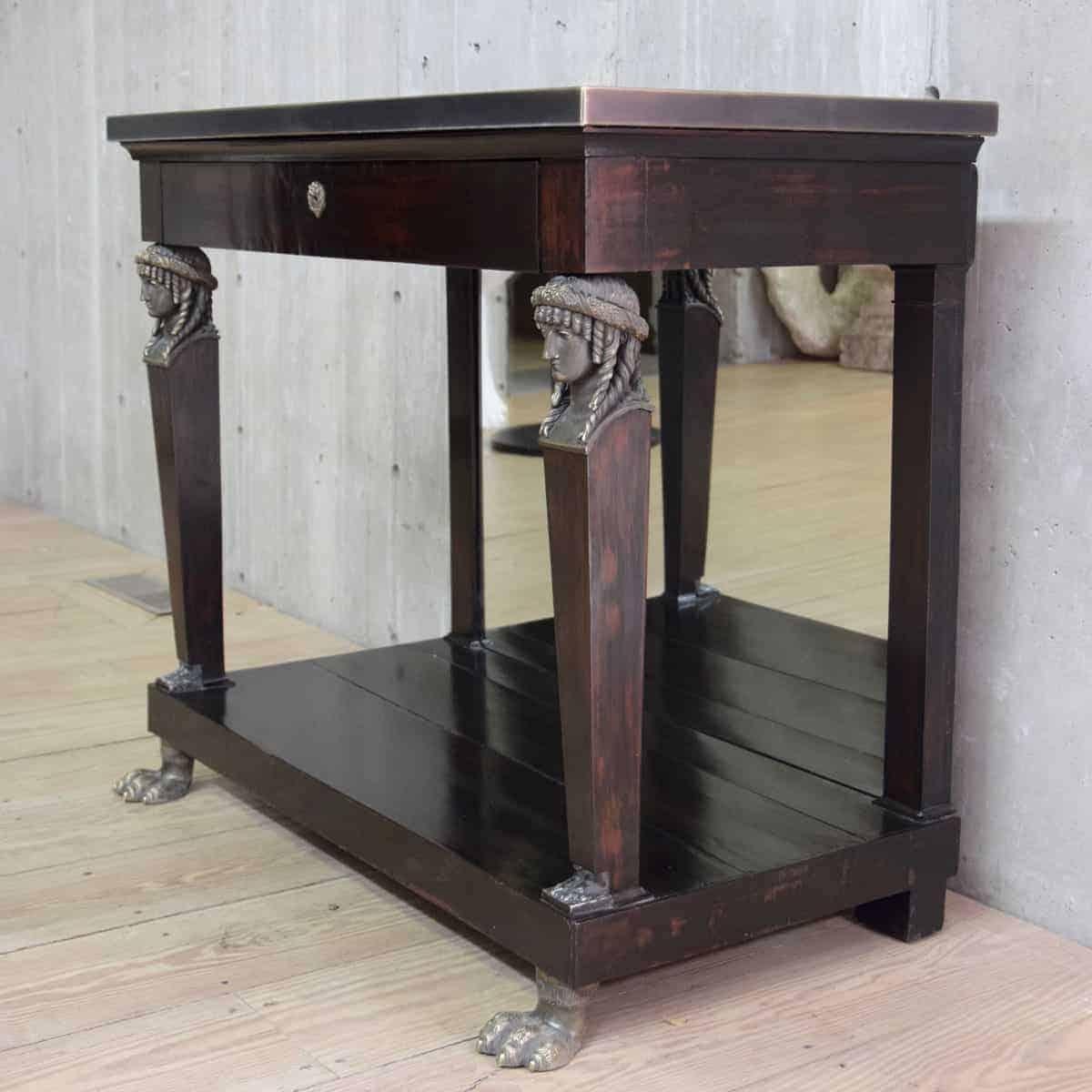 A 19th Century blackened mahogany console in the Empire style.  Bronze caryatid supports, paw feet, and lion keyhole.  The key is lost in time but the drawer does open.  Console has lower shelf with some splitting.  Mirrored back.  Top is newly made