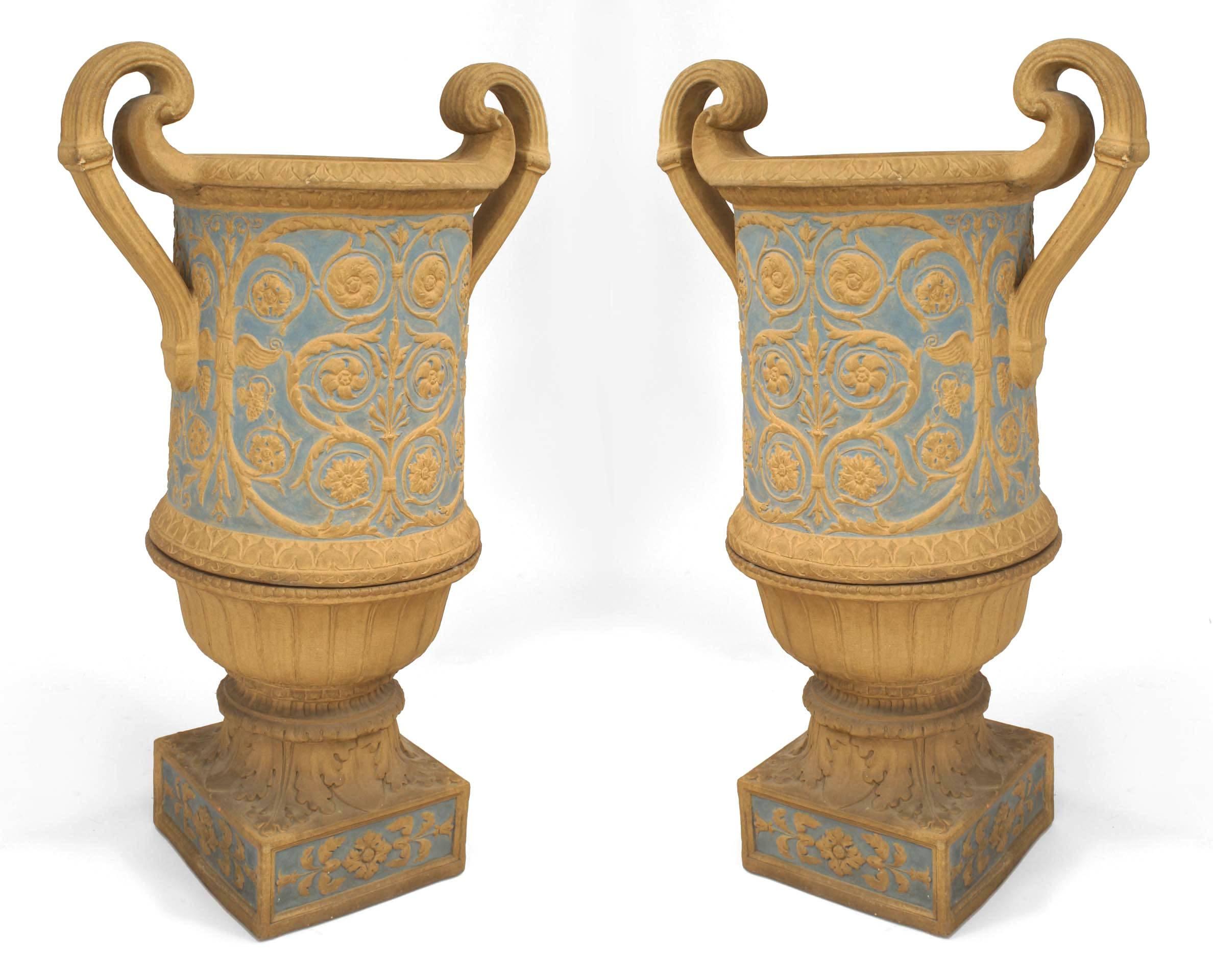 Pair of Neoclassical English Adam style (19th Cent) coade stone urns resting upon square bases with a blue-painted floral and scroll designs and fluted side handles.

