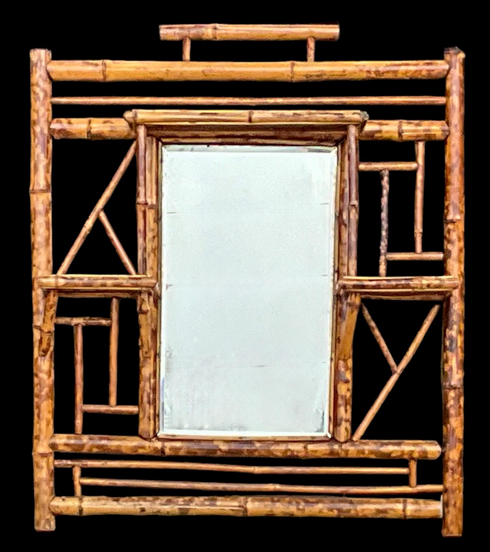 Dies ist ein englisches Wandregal aus gebranntem Bambus aus dem späten 19. Jahrhundert mit einem Spiegel in der Mitte. Die drei kleineren Regale sind jeweils mit schwarz und rotbraun lackierten Verzierungen versehen. Das Regal hat altersgemäße