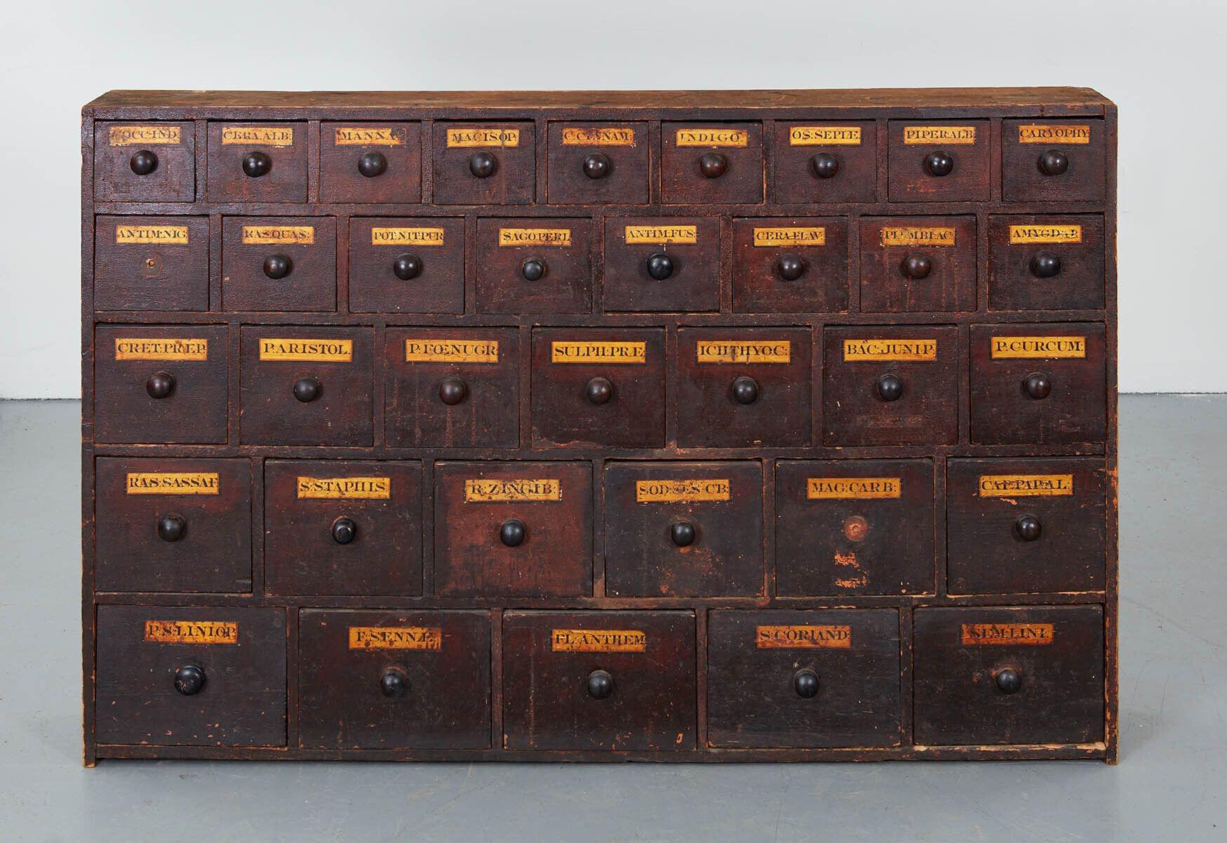 An apothecary cabinet from an English pharmacy, circa 1850. Desirable thin and narrow dimensions with graduated tiers of 9 drawer row over 8 drawer row over 7 over 6 and at bottom over 5 drawers. Original hand painted black on gilt lettering on