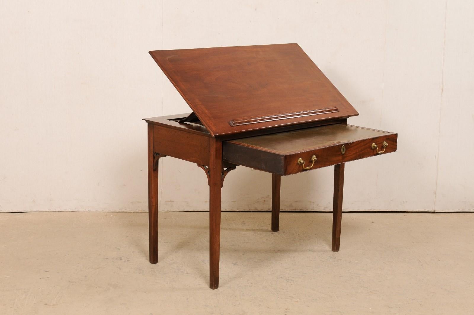 A fabulous English architect's desk with green leather writing pad and dual tilt top from the 19th century. This antique Late Georgian table from England, created of mahogany, is big on design, craftsmanship and functionality; featuring a top with