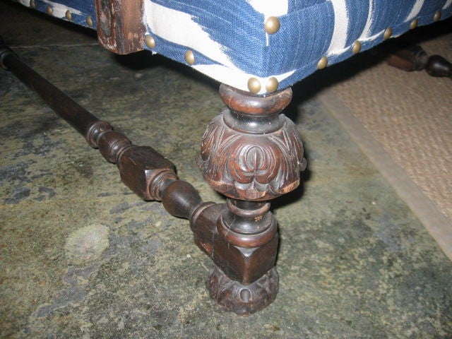 Detailed carving on exposed wood of antique armchair. Newly upholstered in rich blue and white Ikat fabric with nailhead trim. Turned stretchers and deep seating.