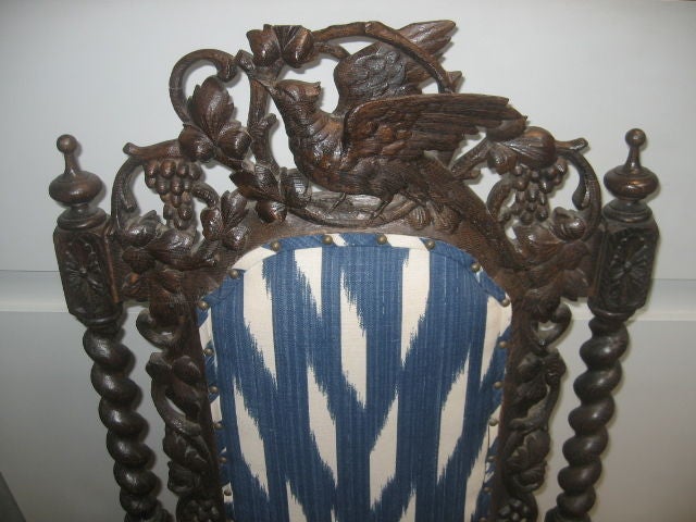 Important hall chair with ornate carving. Crest rail has carved details of a bird amongst grapevines. Barley twist side supports with ornate capped finials. Hand carved lion heads create the supports for the arm rests. Newly upholstered in blue and