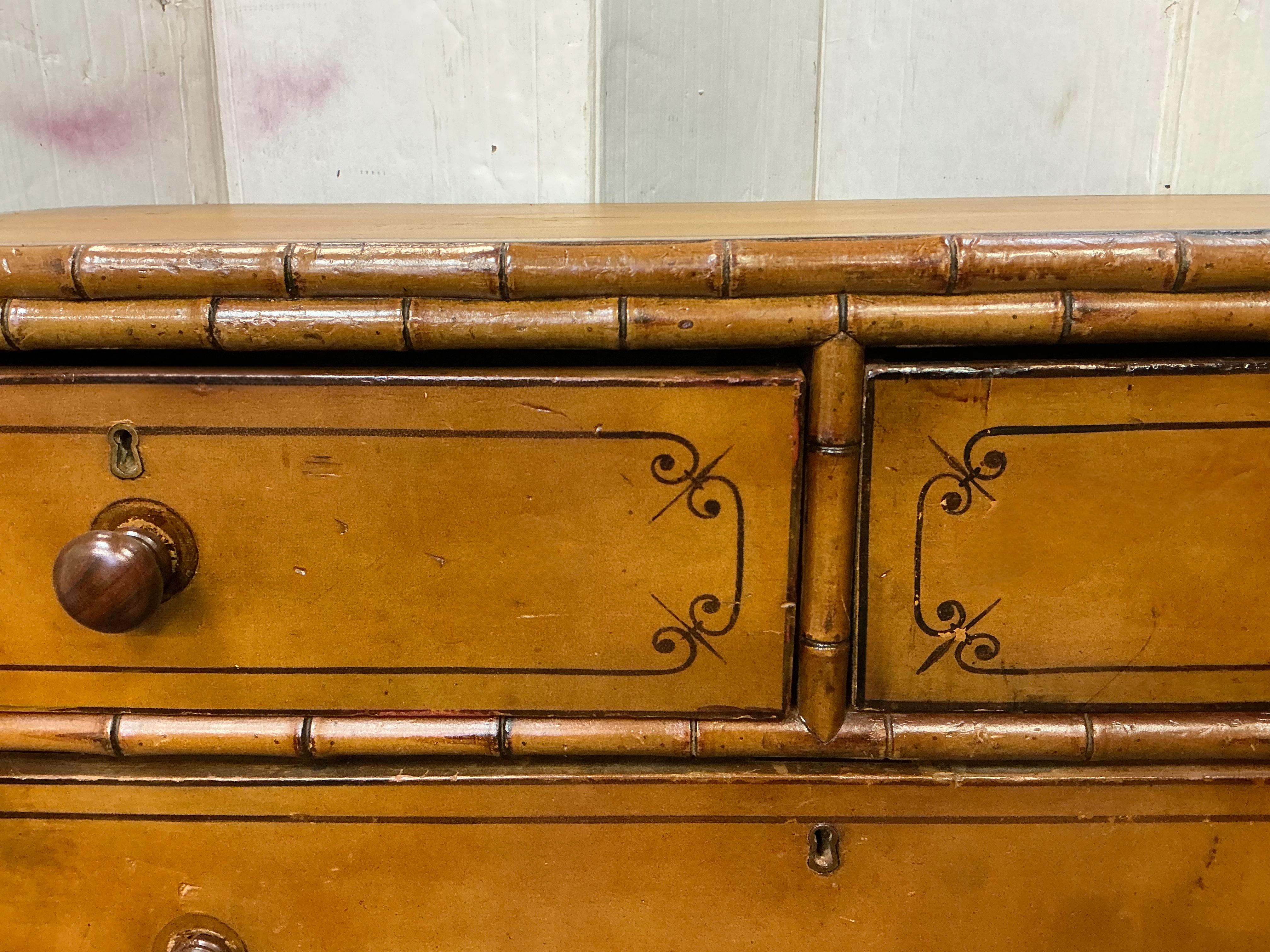 This is a 19th century English faux bamboo carved and painted faux bamboo chest. It is both stained and painted. It has the original turned feet and knobs. The drawers are dovetailed. There is age appropriate wear through the piece. The locks do not