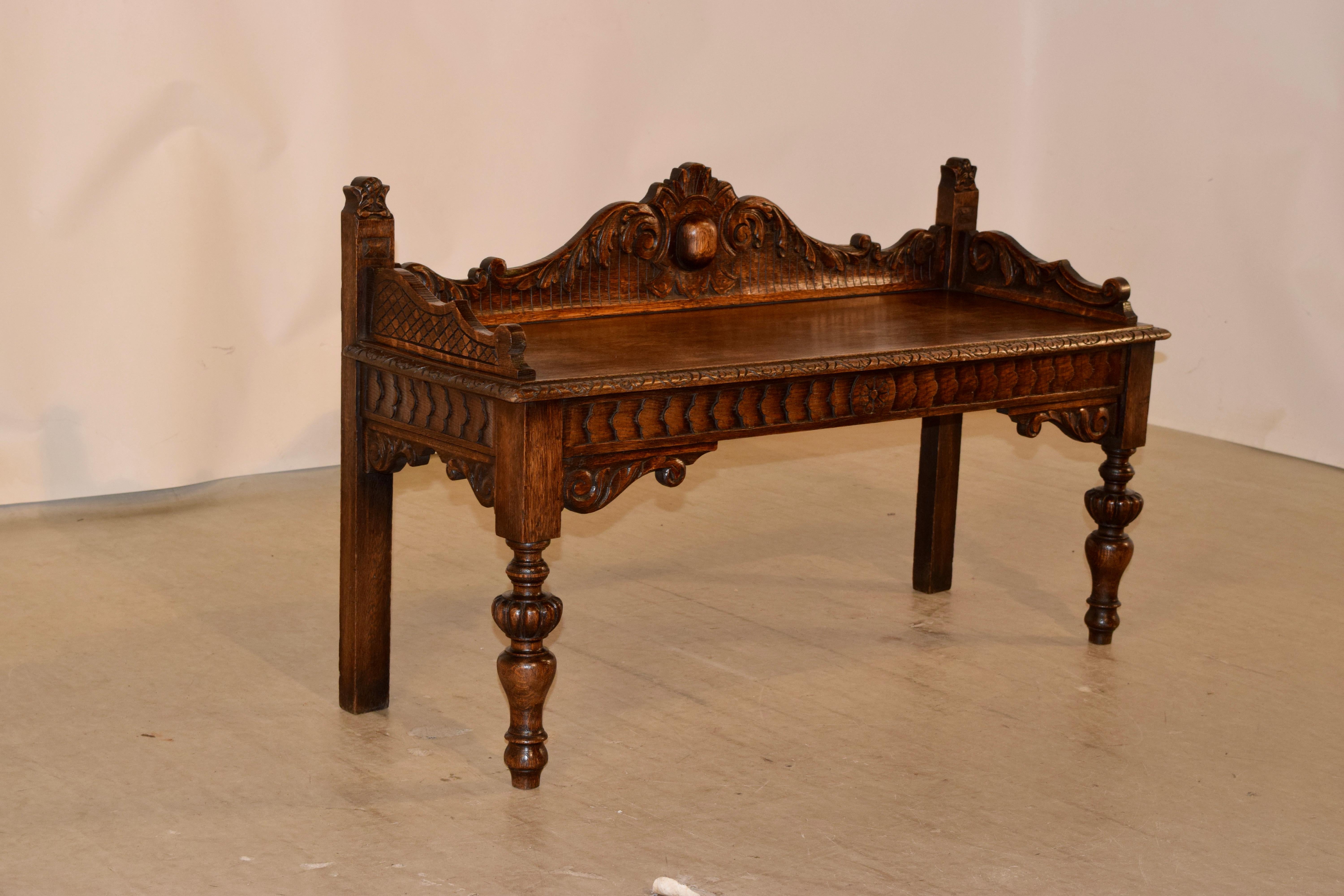 19th century oak window seat from England with wonderfully hand carved and scalloped back and sides. The seat has a carved and beveled edge, following down to a hand carved decorated apron and supported on hand turned legs in the front and simple