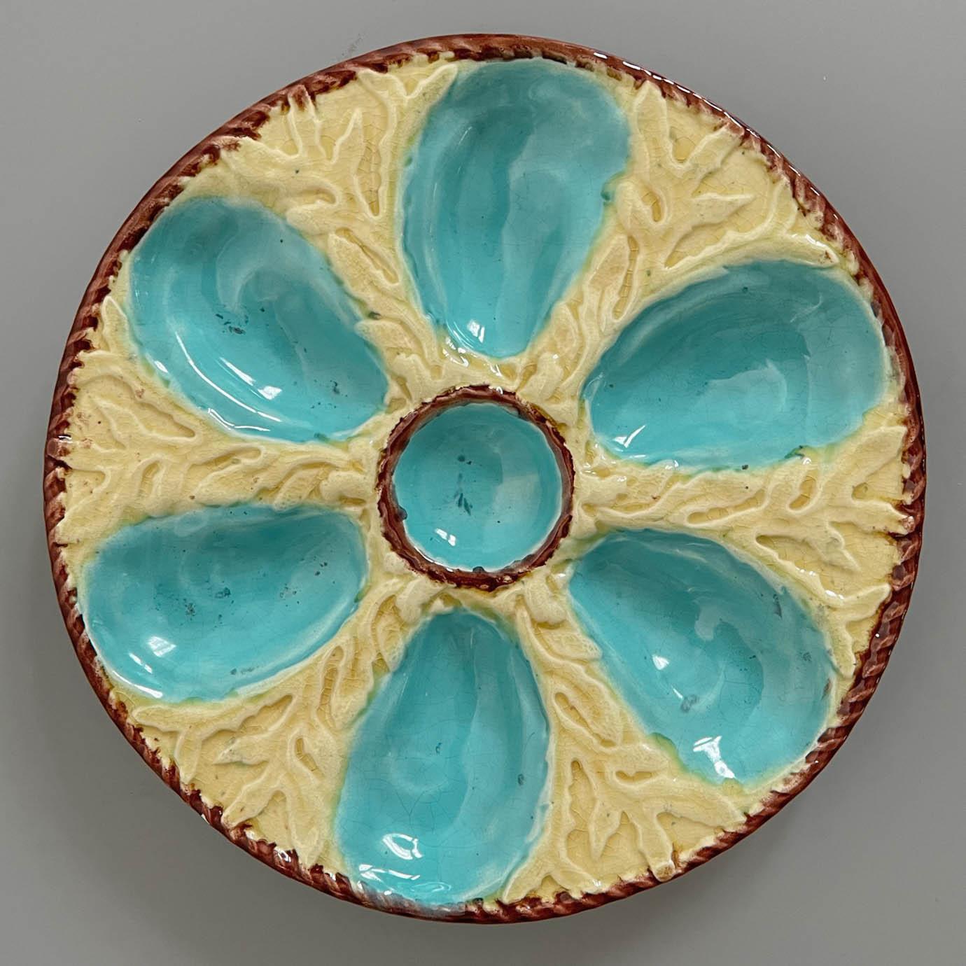 A 19th Century English glazed majolica oyster plate with six turquoise blue oyster wells surrounding a center well for sauce on a yellow ground with seaweed relief. A brown nautical rope border encircles the center well and the outer rim. The verso