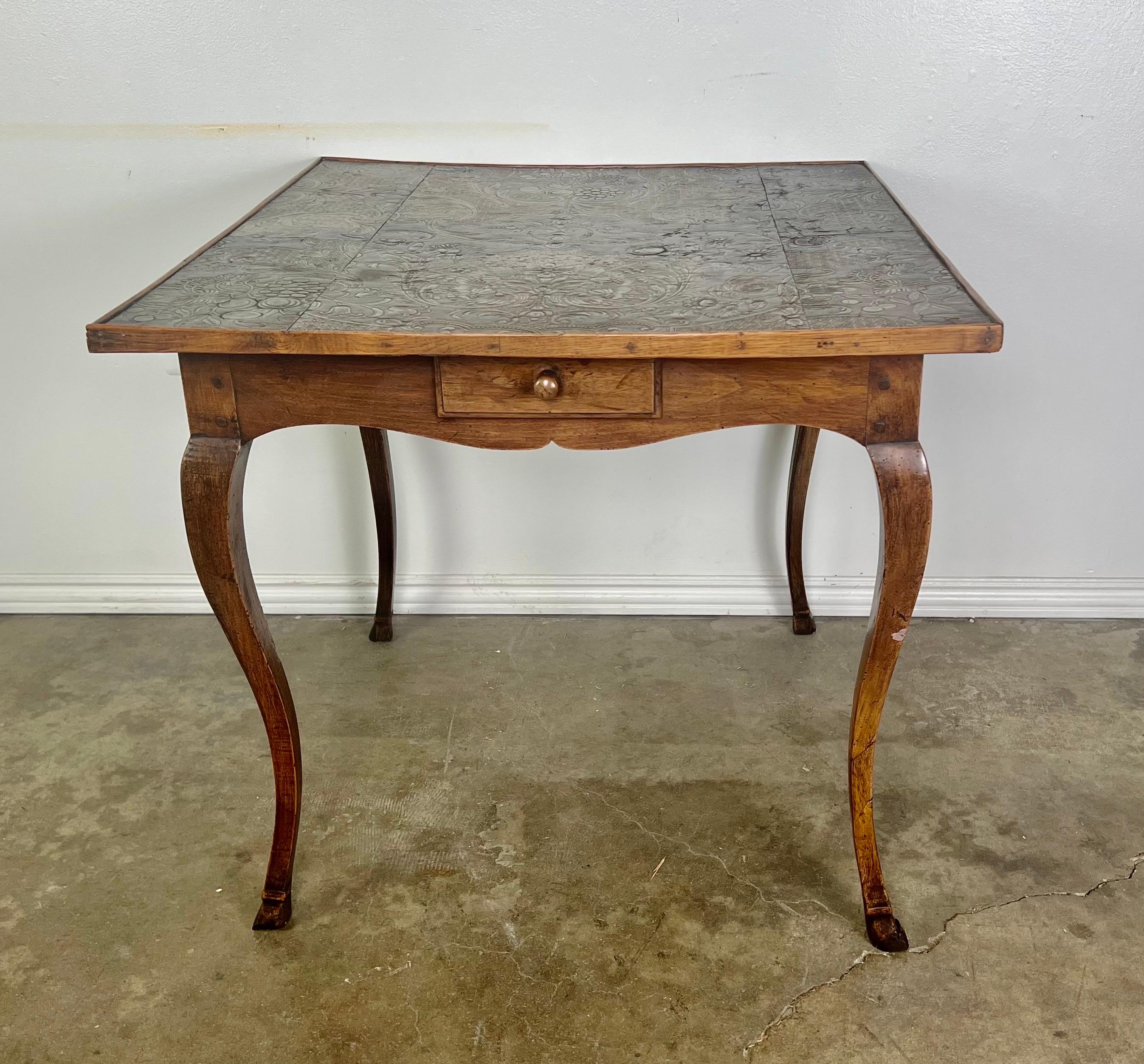 19th century French game table with four drawers ana a leather embossed top., The table stands on four cabriole legs with hoof feet.