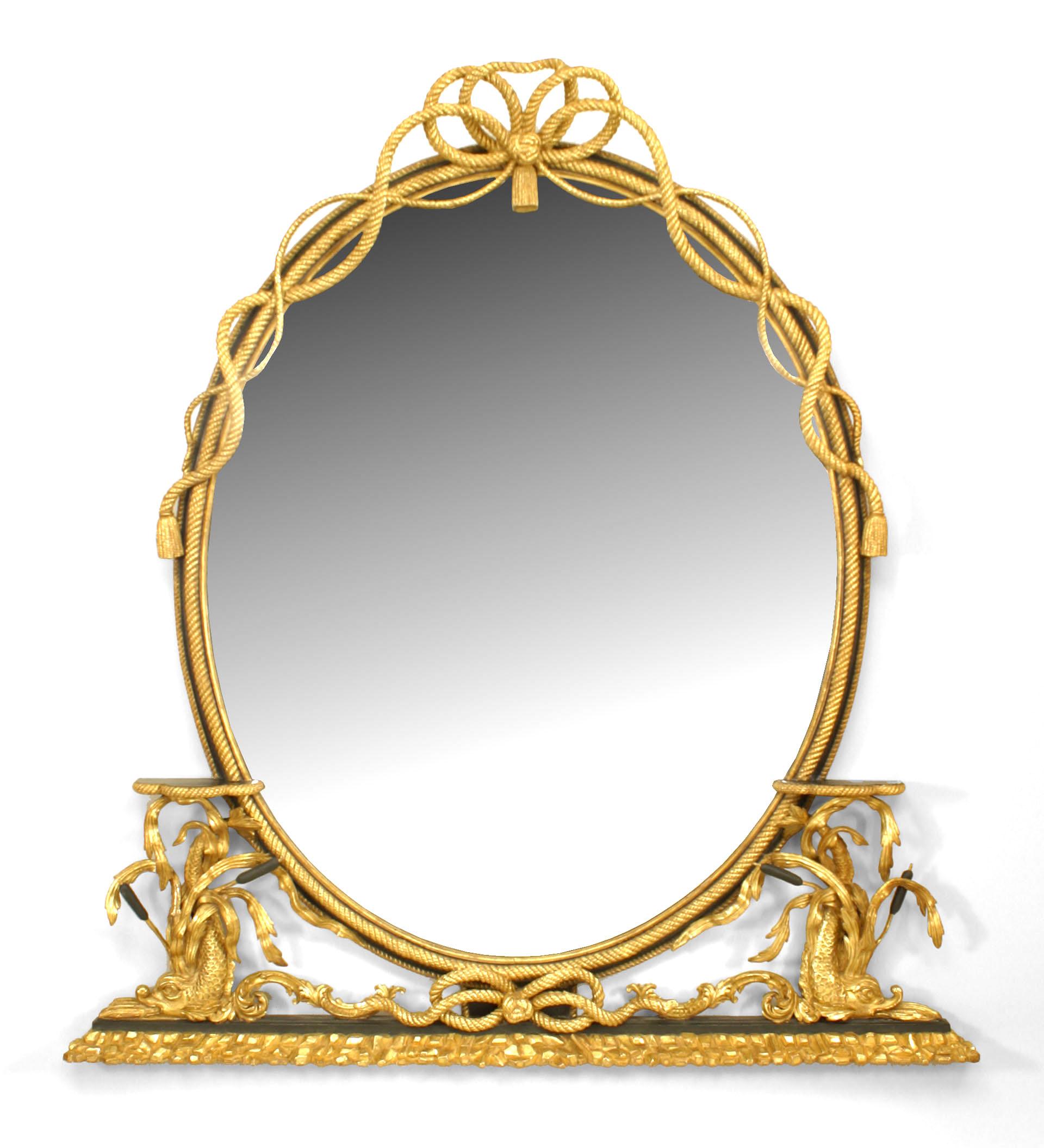 English Georgian (19th Century) gilt and ebonized trimmed oval wall mirror with a carved gilt rope border, bow knot top, and dolphin support side shelves.

