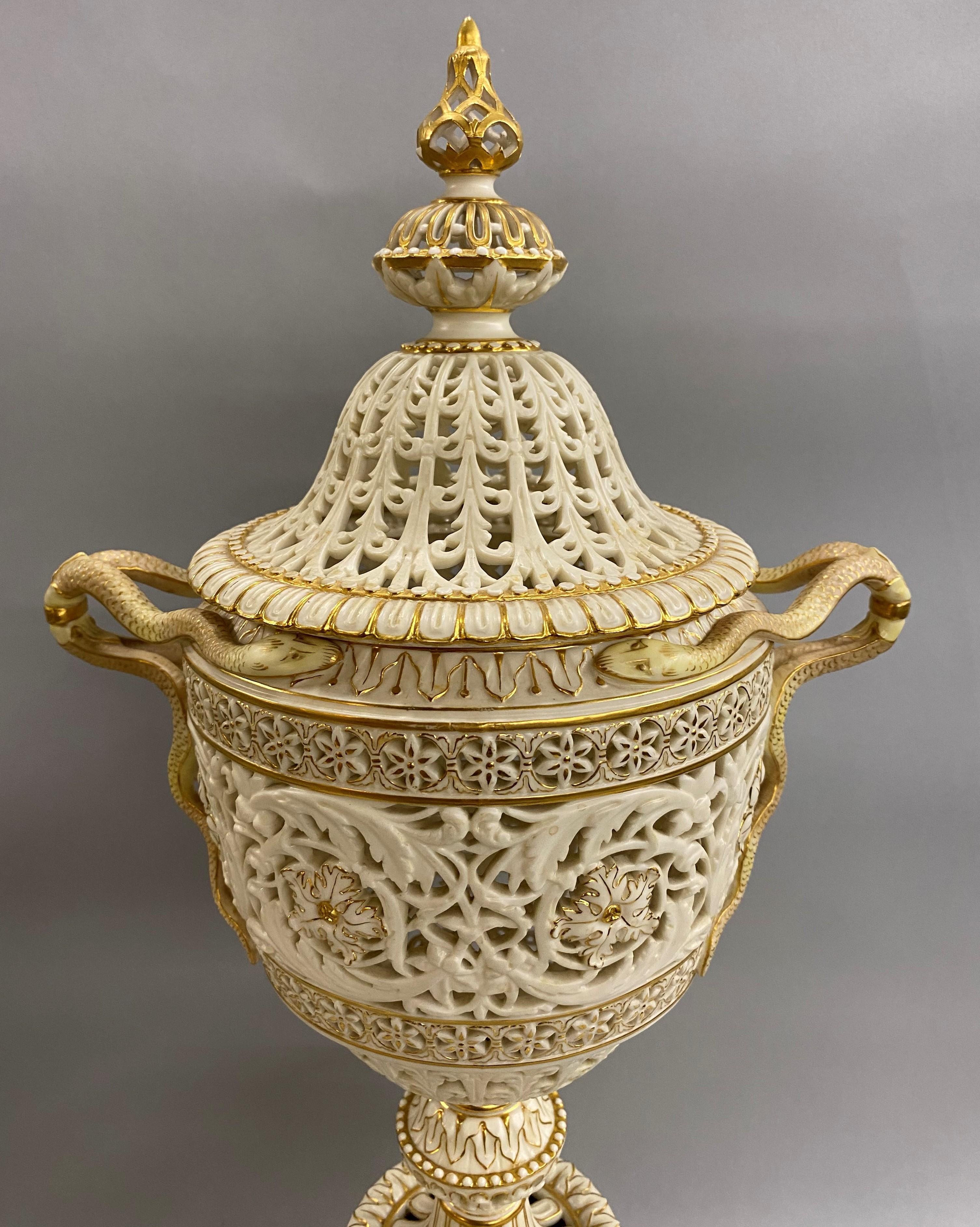 An exceptional large English gilt ivory porcelain reticulated covered urn or centerpiece with finely detailed serpent handles on an out-swept scroll footed base, with the Grainger & Co Royal China Works Worcester England hallmark under both the lid