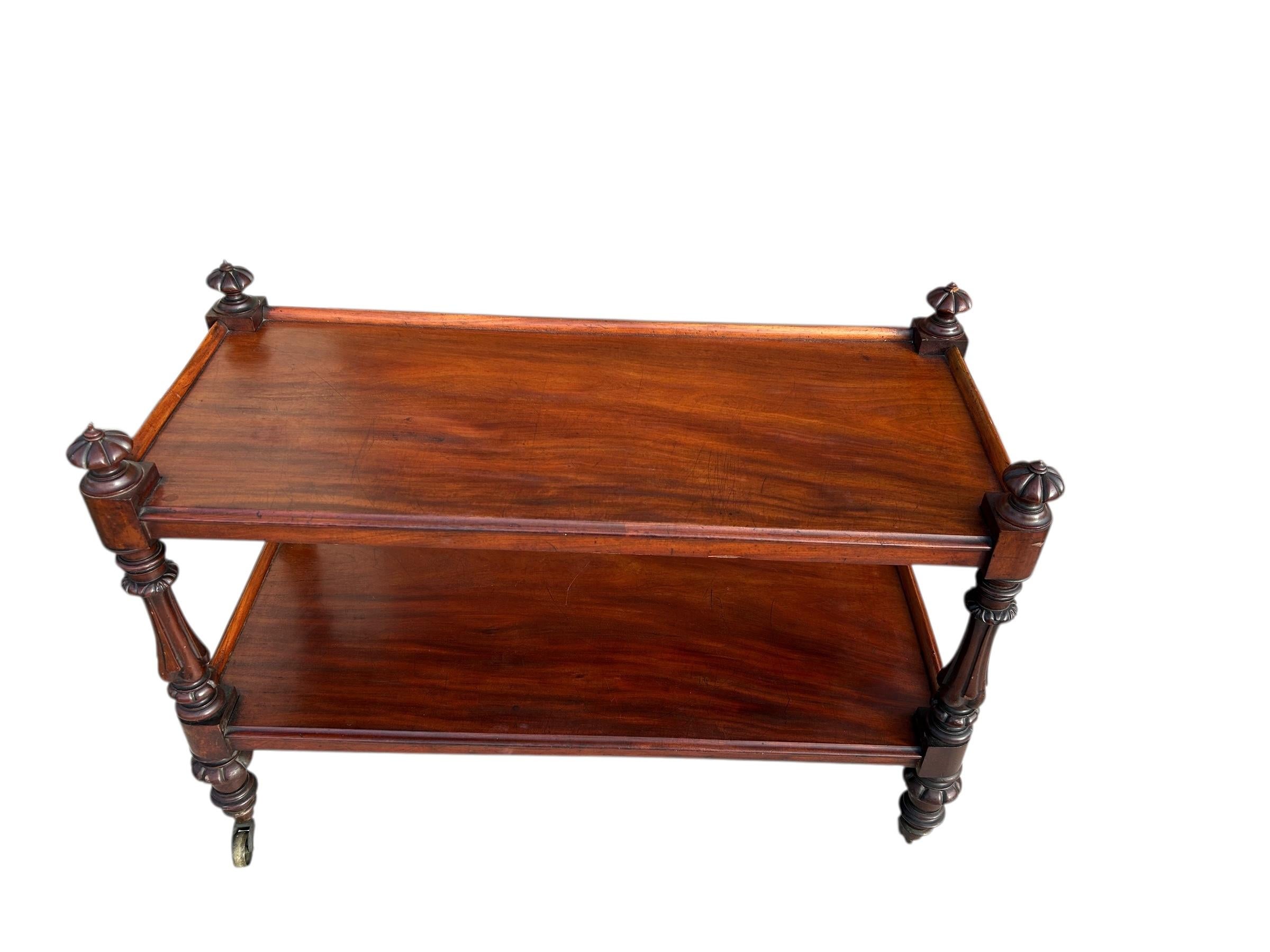 Un carrello inglese di dimensioni insolite della metà del XIX secolo. Il mogano intagliato è ricco di colore e presenta due ripiani a più livelli. Le quattro gambe sono tornite e con finimenti splendidamente cesellati. Il carrello è dotato di grandi