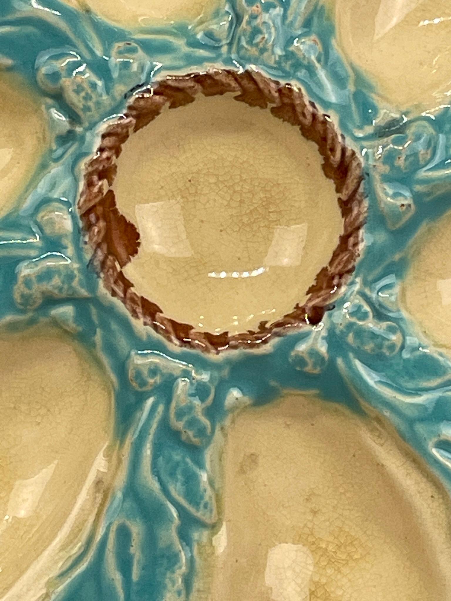 A 19th c English oyster plate with six-well majolica glazed oyster plate by Fielding & Co. Ltd., Stoke-on-Trent, England, circa 1875-1880.. Cream oyster wells surround a center well and light turquoise seaweed. A light chocolate brown nautical rope
