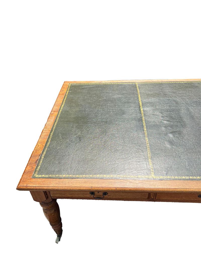 19th C English oak conference table, desk or dinner table

English conference table, desk or dinner table, made of oak from the 19th century, ca 1880-1890 with a green leather top with gold print, raised on tapered legs on castors. 
Ten drawers in