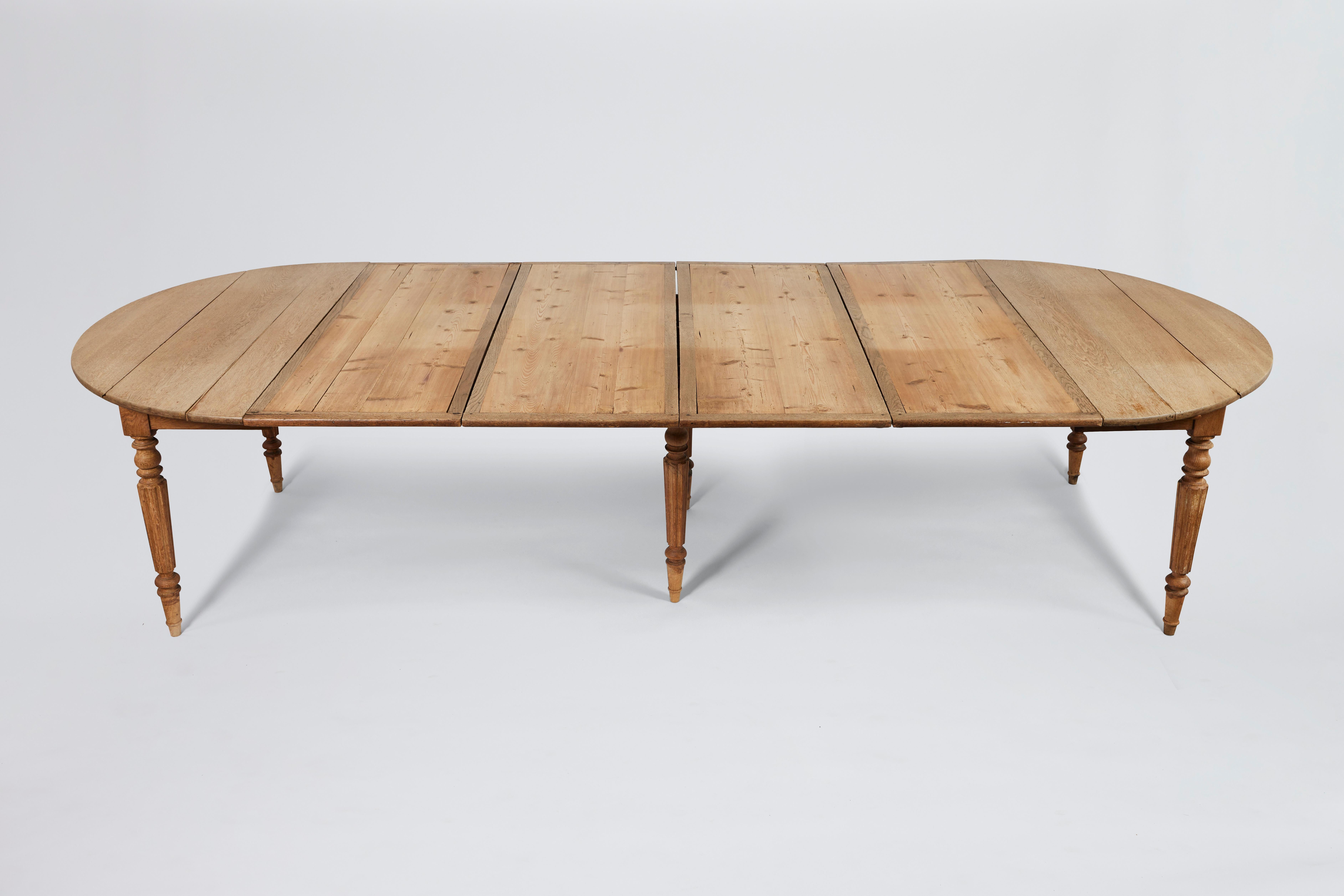 19th Century English Georgian-style oak expandable dining table with four leaves, sitting on five (5) carved reeded legs. 

4 leaves, each 20.25