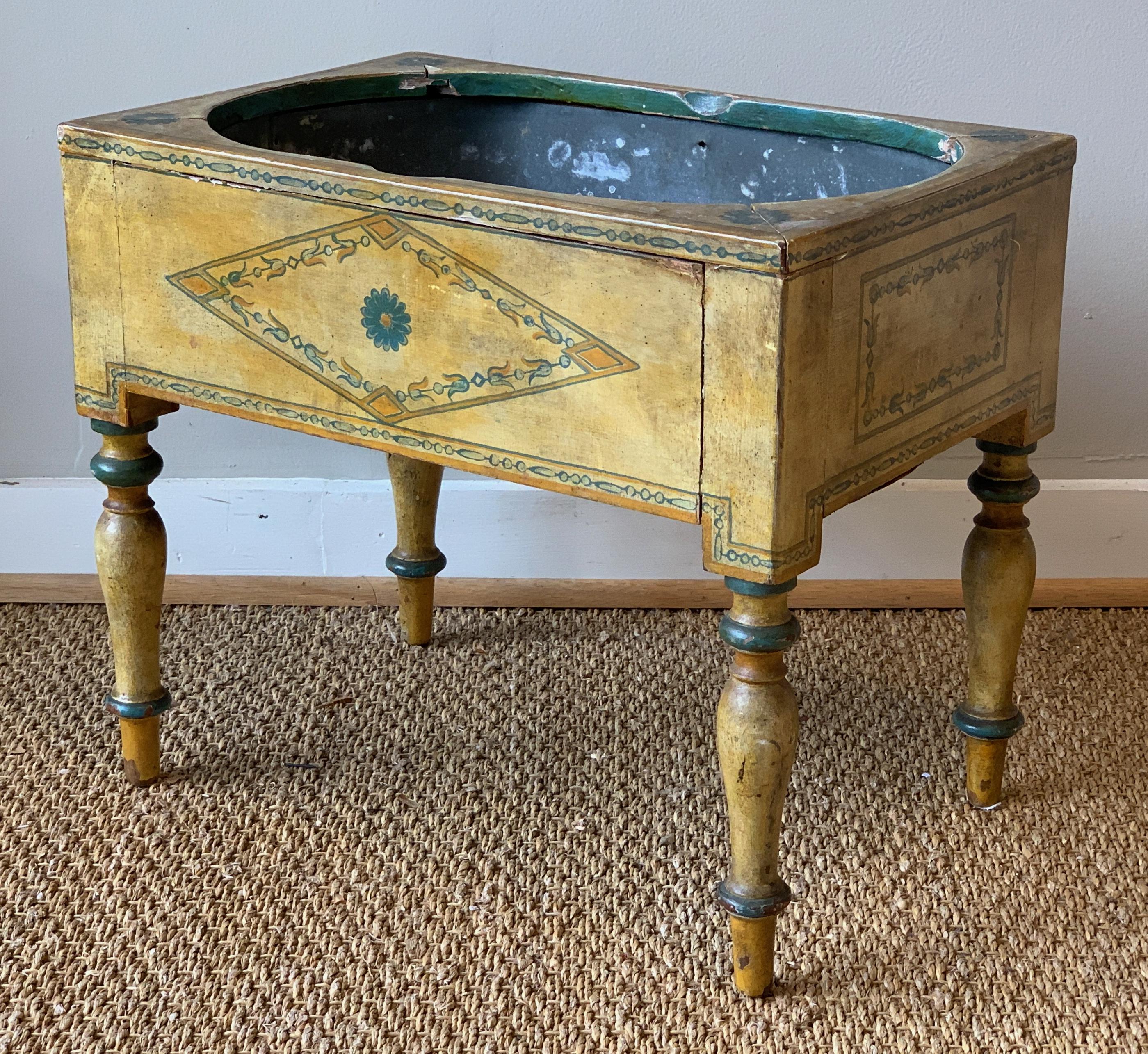 A small and charming early 19th century English paint decorated zinc lined planter. The entire surface in a muted mustard yellow with subtle green and gold accents.