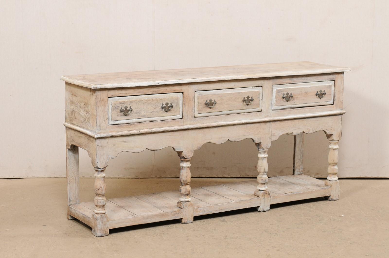 An English carved and painted wood console table, with drawers and lower shelf, from the 19th century. This antique table from England features a rectangular-shaped top over a case which houses three raised-panel drawers, set horizontally along the