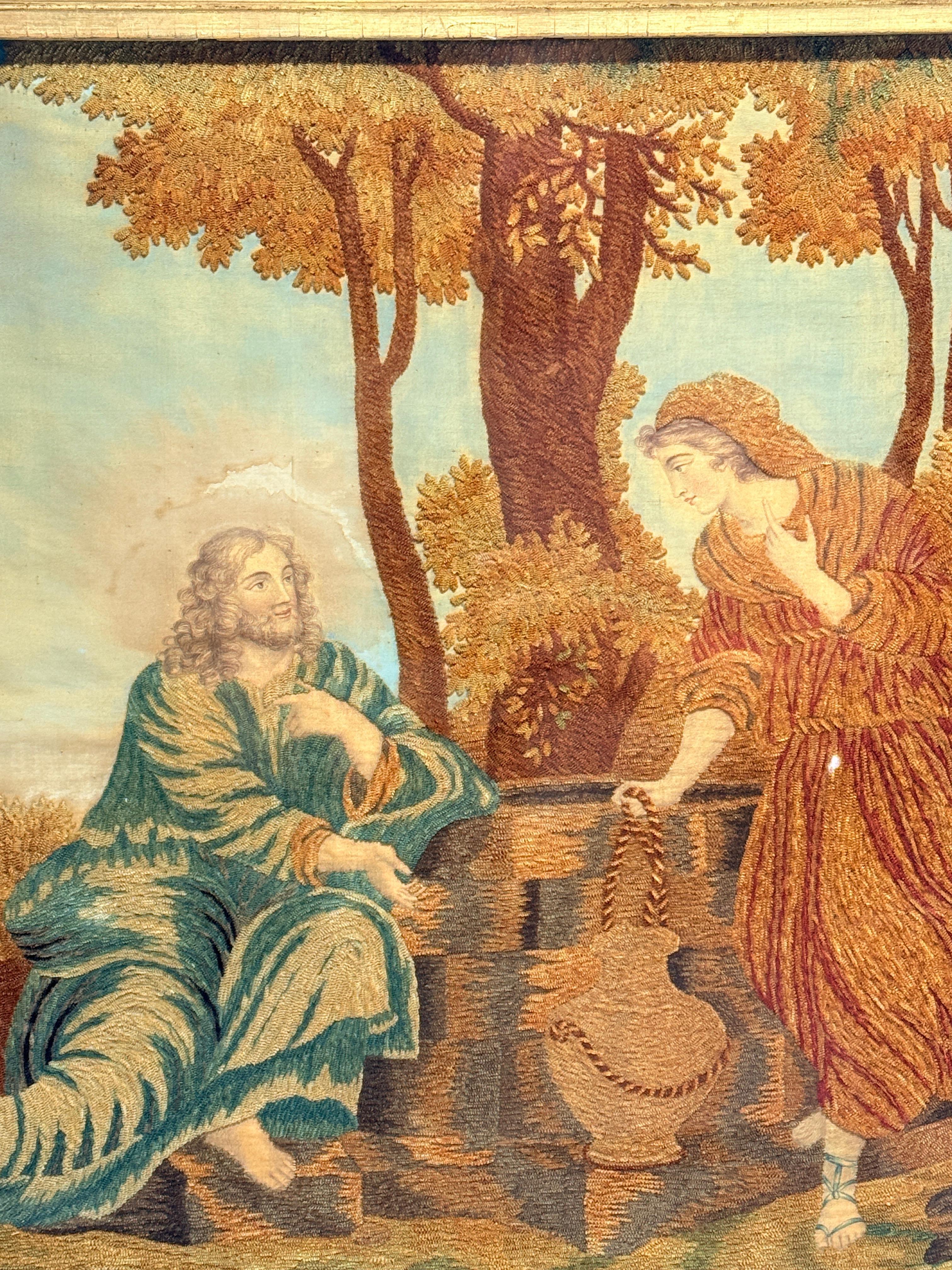 Diese fein ausgeführte religiöse Stickerei aus dem 19. Jahrhundert stellt die biblische Szene von Christus und der Samariterin am Brunnen dar, ein Thema, das bei den viktorianischen Stickern unter dem Einfluss der präraffaelitischen religiösen