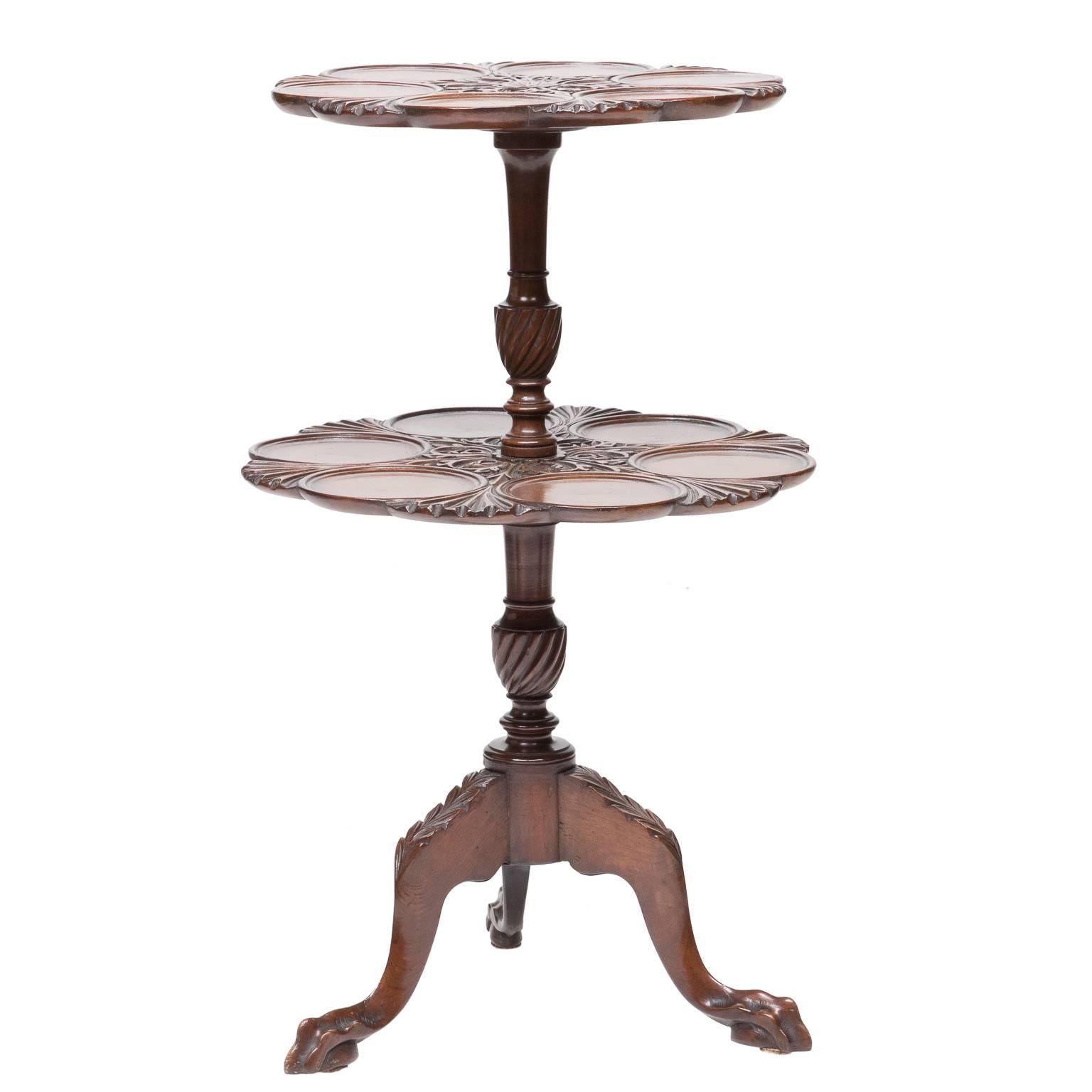 A Chippendale mahogany two-tier dessert side table. Shaped edges to the shelves, well-carved tops, and round plate holders. Resting on a tripod base and ending with a claw and ball foot. Acanthus leaf carvings to each knee of the legs. Finely turned