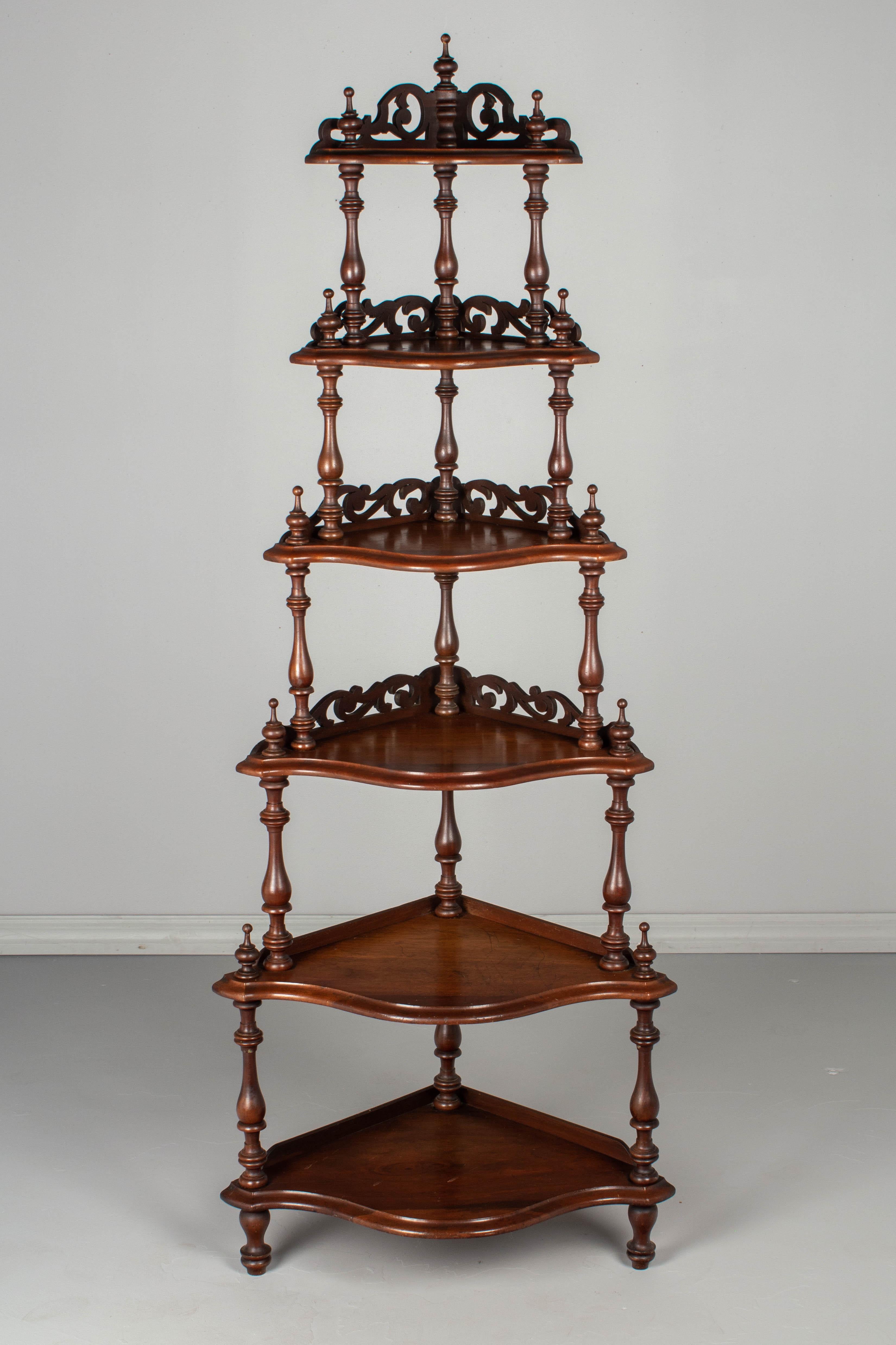 A late 19h century English Victorian mahogany corner étagère with six shelves of graduating width. Decorative turned spindle columns connect the shaped shelves, each with decorative openwork wall cut-outs and corner finials. The spindles will be