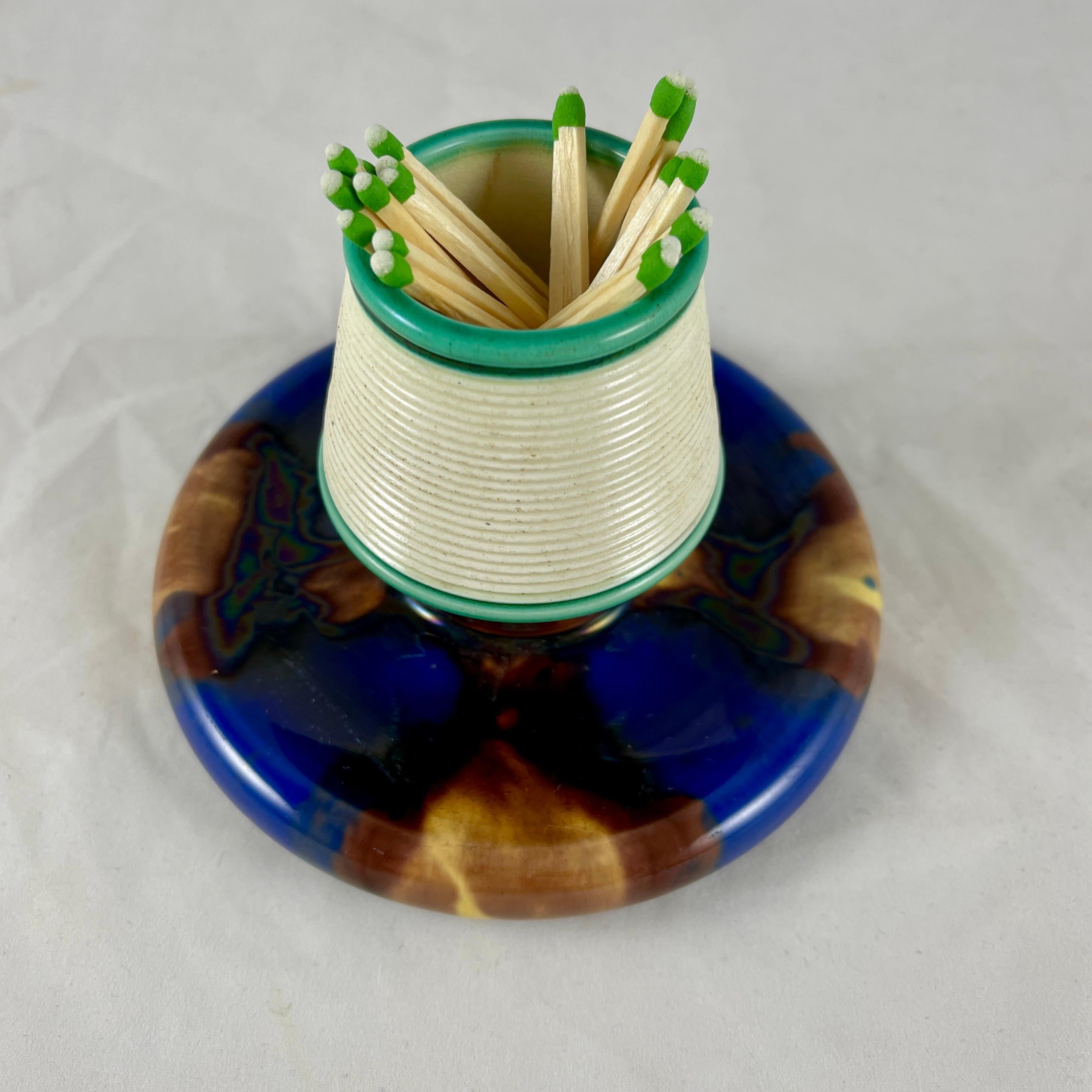A Wedgwood Majolica earthenware pottery match holder and striker, Staffordshire, England – date marked 1869.

For the hearth, kitchen or bedside, the holder is ribbed for lighting strike-anywhere matches, the bottom tray is for the spent sticks.