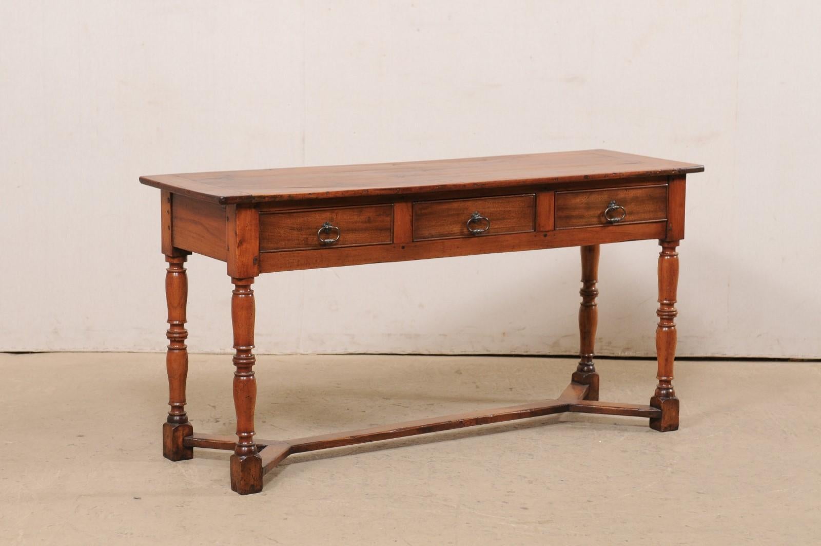 An English carved wood console table with drawers from the 19th century. This antique table from England features a rectangular-shaped top over a case which houses three small drawers, set horizontally along the front, and is presented upon four
