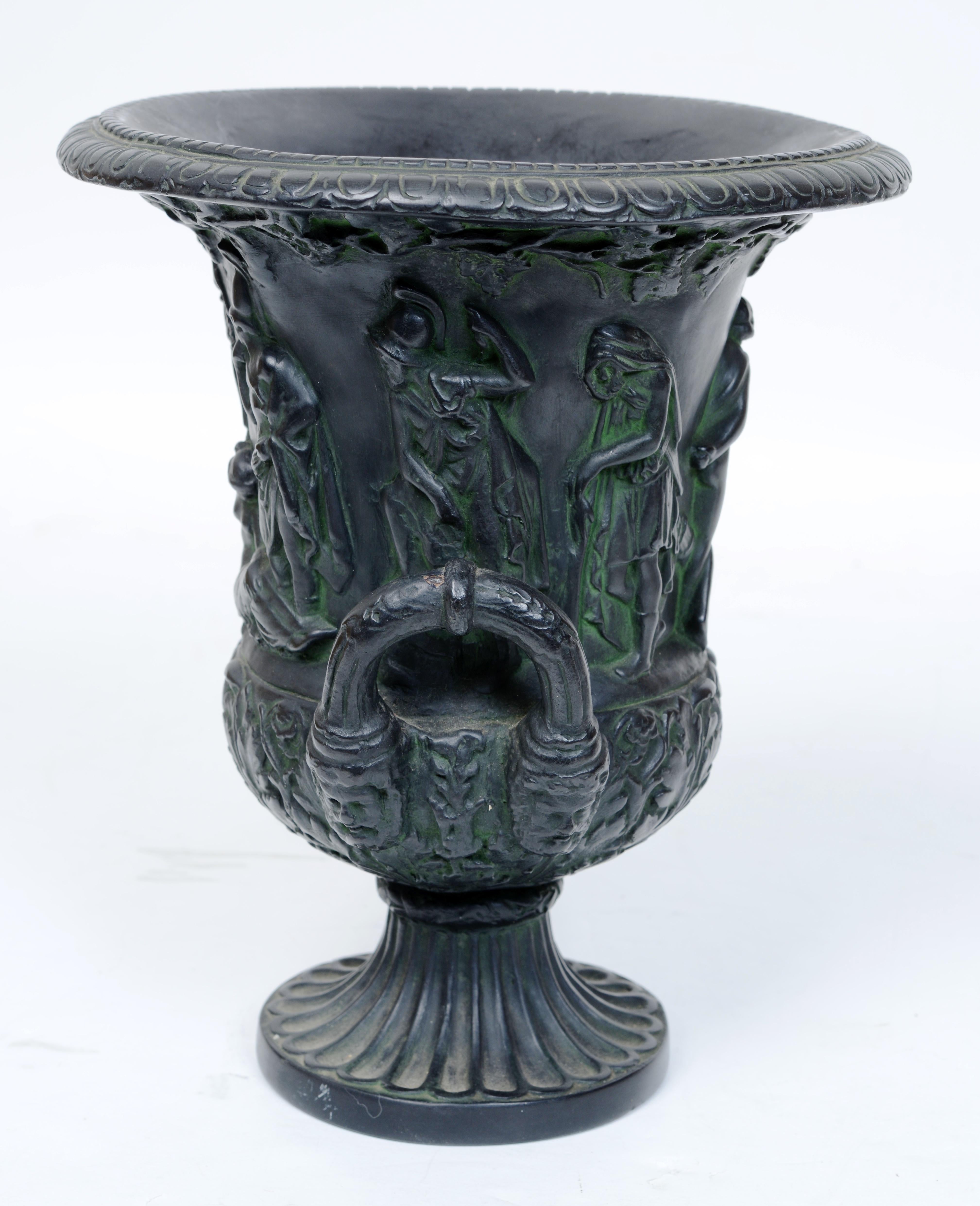 19th c Faux Bronze Painted Black Basalt Campagne Shaped Medici Vase.  Two-Handled Urn. Pair of reeded loop handles terminating on bearded masks. The sides with raised Greek figures in various poses and grape vine and leaf borders. This urn is a