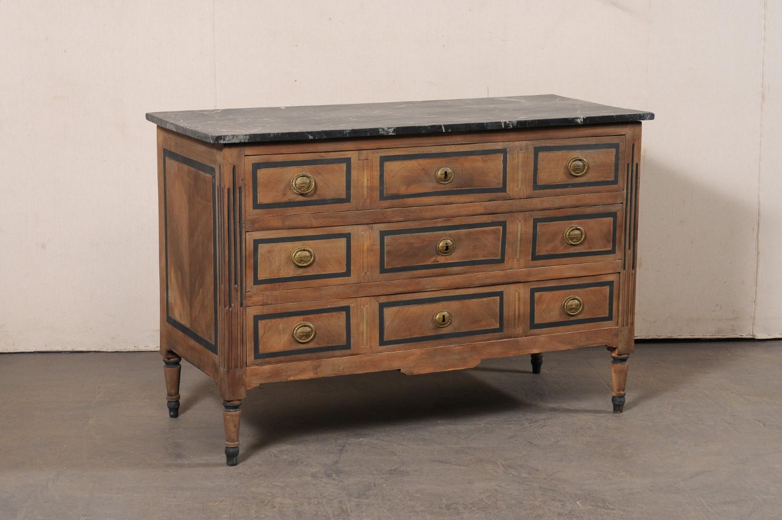 A French Neoclassical chest, with faux marble top and brass hardware, from the 19th century. This antique chest from France features a rectangular-shaped faux-marble top, which overhangs the neoclassical case which houses three full size graduated