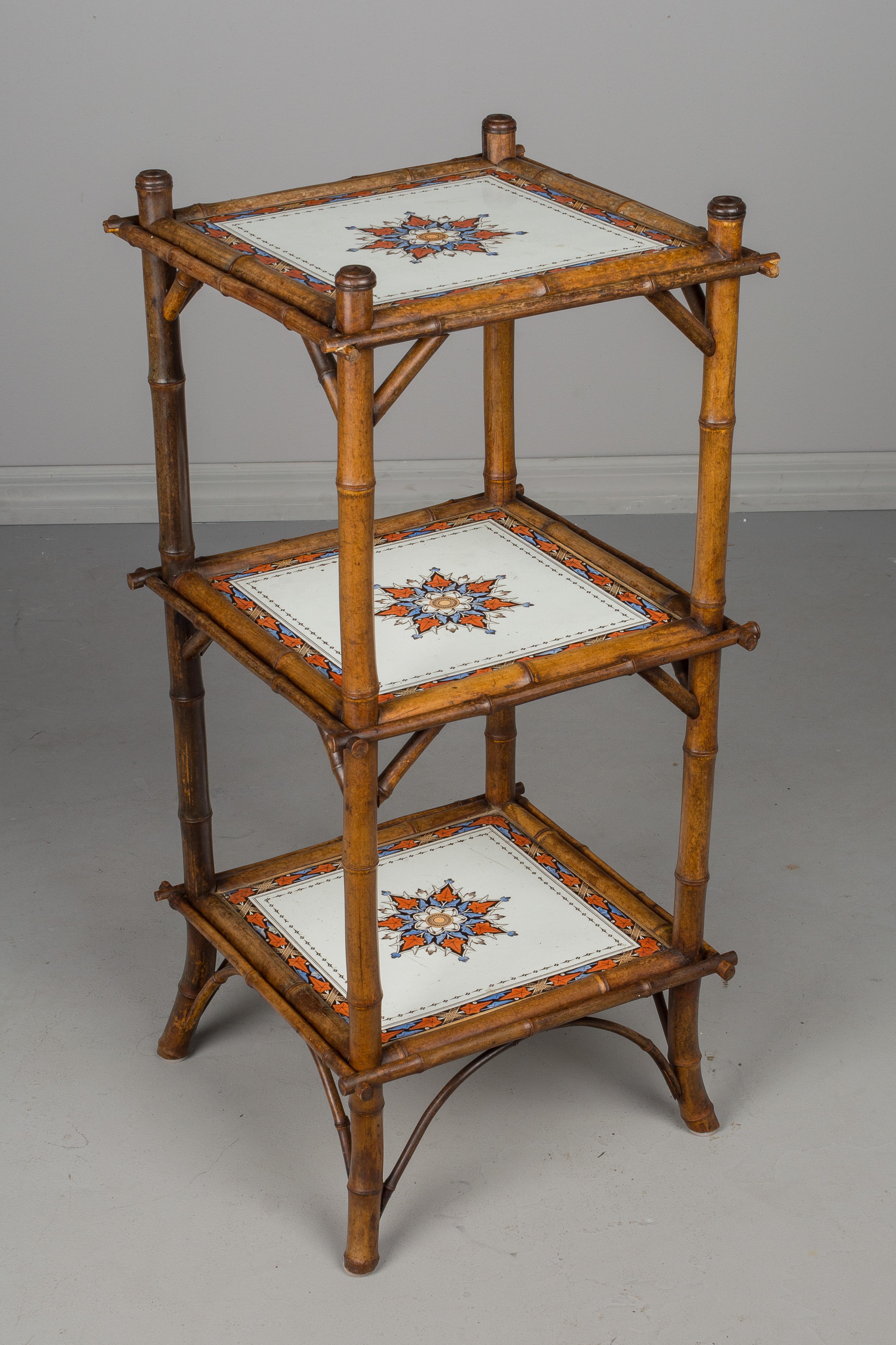 A 19th century French bamboo three-tier plant stand or small étagère with ceramic tile shelves. Space between shelves is 11.25