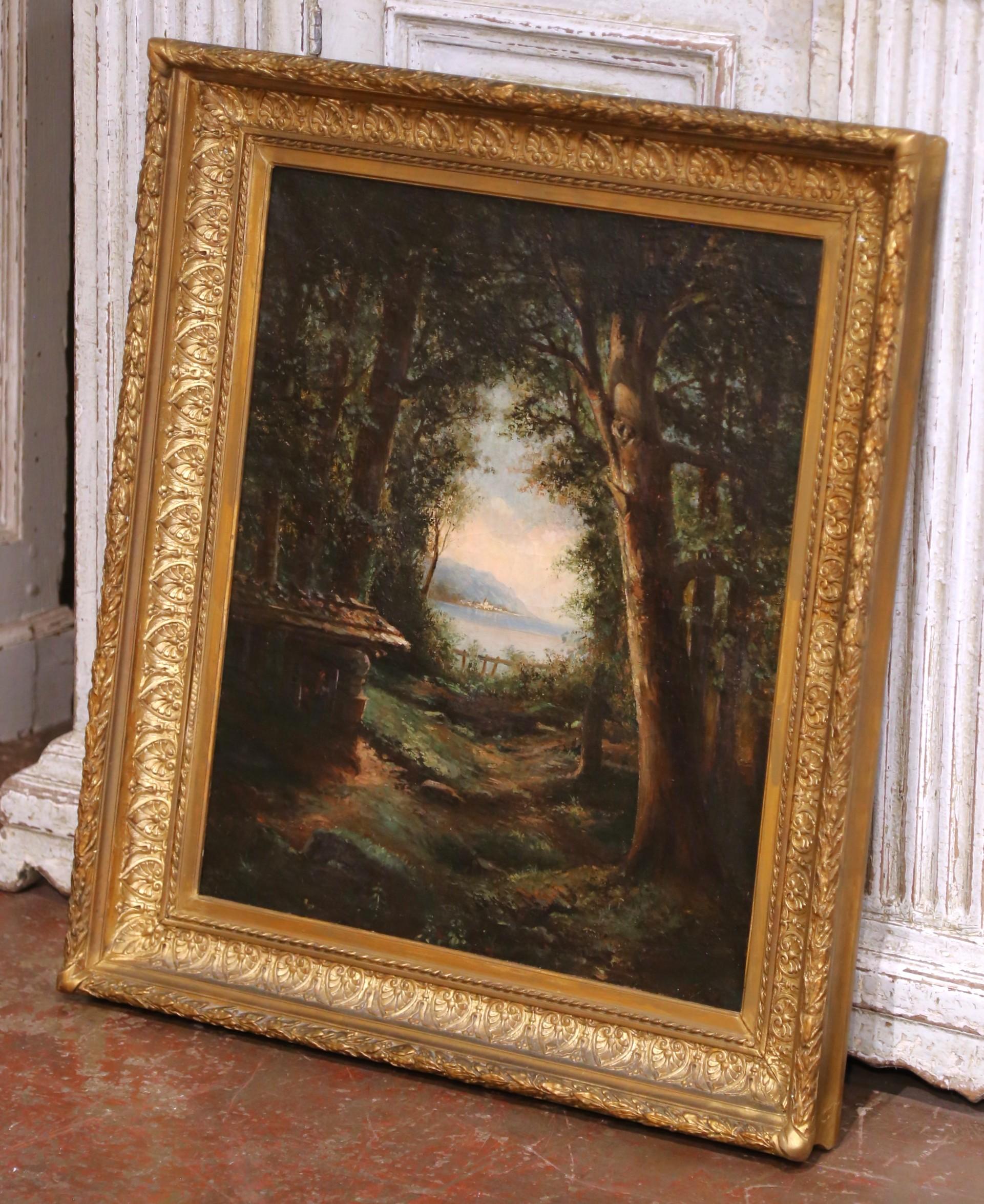 Dieses stimmungsvolle antike französische Ölgemälde auf Leinwand aus der Zeit um 1870 zeigt eine wunderschön wiedergegebene Waldlichtung, die sich zu einem schimmernden See und fernen Bergen hin öffnet, wahrscheinlich in der Region Rhône-Alpes. Die