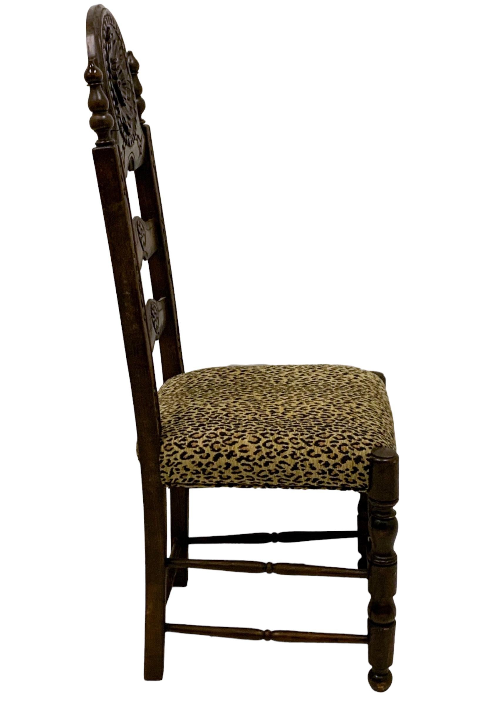 This is a pair of 19th century French carved oak side chairs. They have a vintage leopard upholstery that does not have any tears. The backs have a carved floral medallion. The ladder back frames are sound. There is a general age appropriate wear.