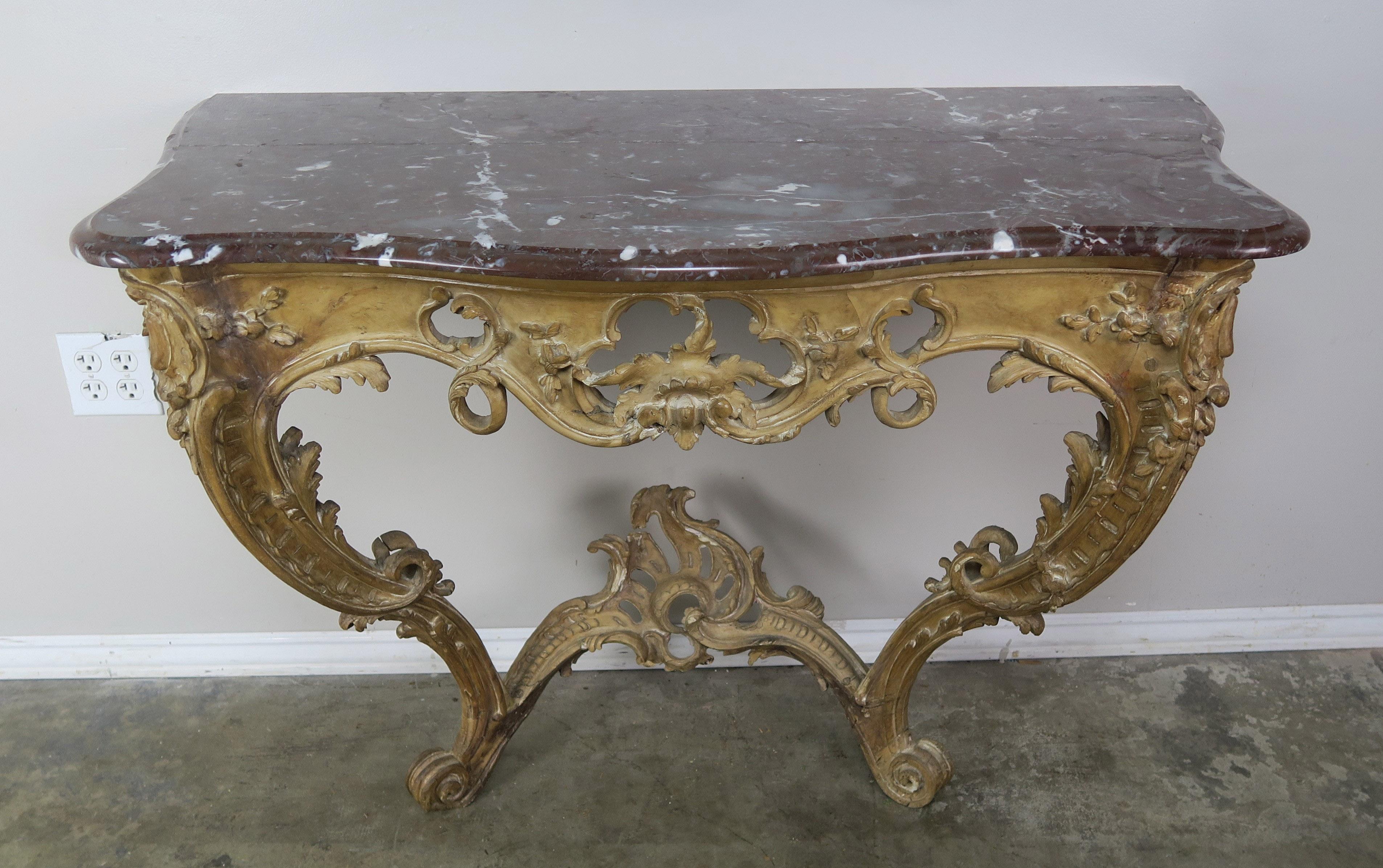 19th century French carved wood console with marble top. The console stands on two ornately carved cabriole legs that end in rams head feet. Carved acanthus leaves throughout. The tops is a beautiful brown & white marble with a single ogee &