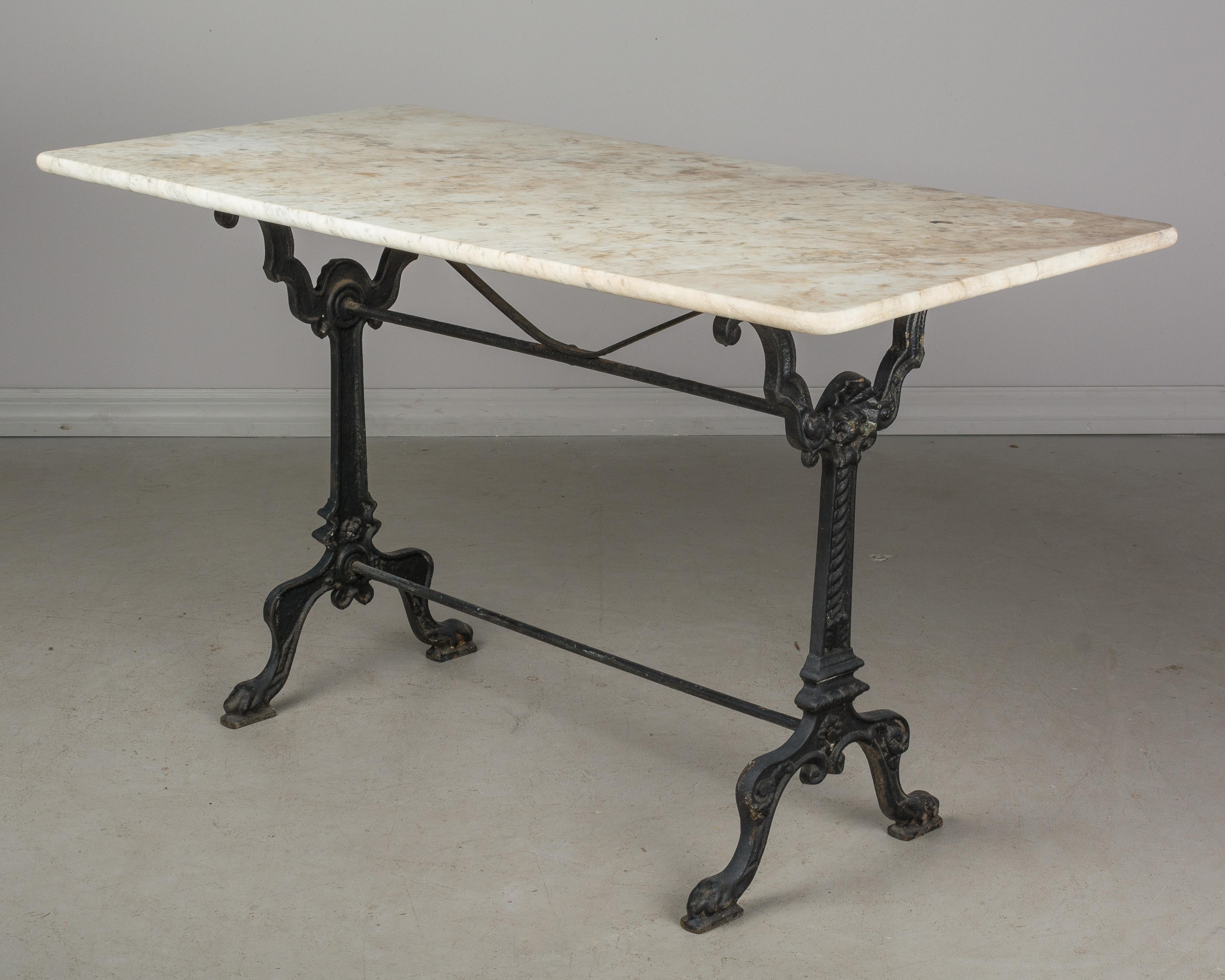 A 19th century French cast iron bistro table with marble top. Nice casting with shell medallion and paw feet. Old black painted patina. Original marble top. Great for indoor or outdoor.