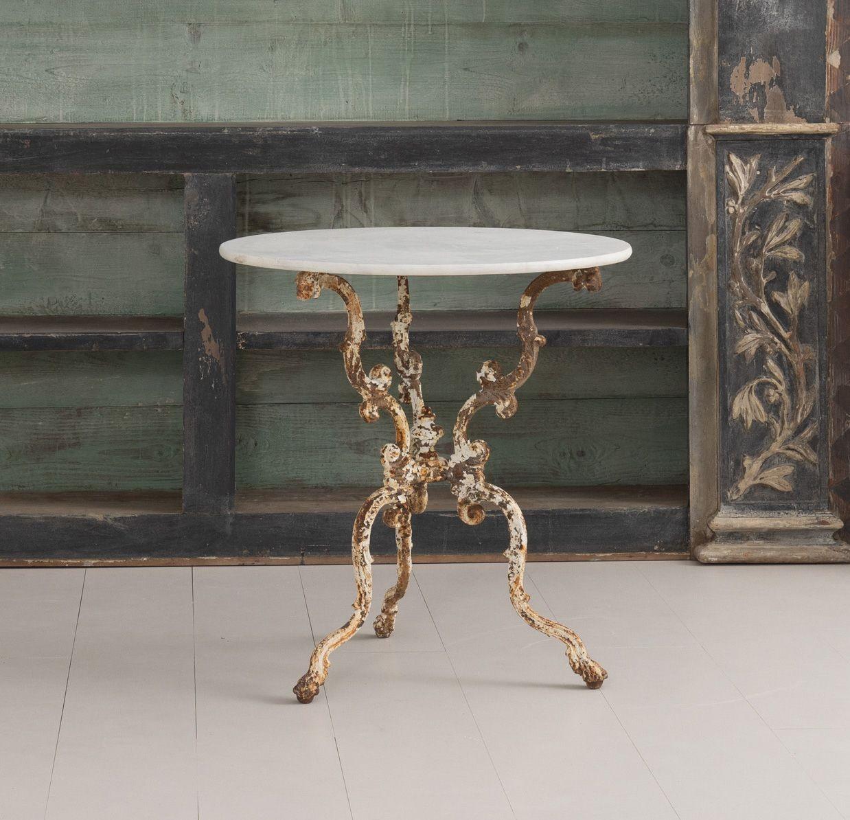 This French cast iron pedestal table has retained its original ivory white painted finish and features a decorative tripod base. The original white Carrera marble top is very lovely with soft gray veining. This table is suitable for either the