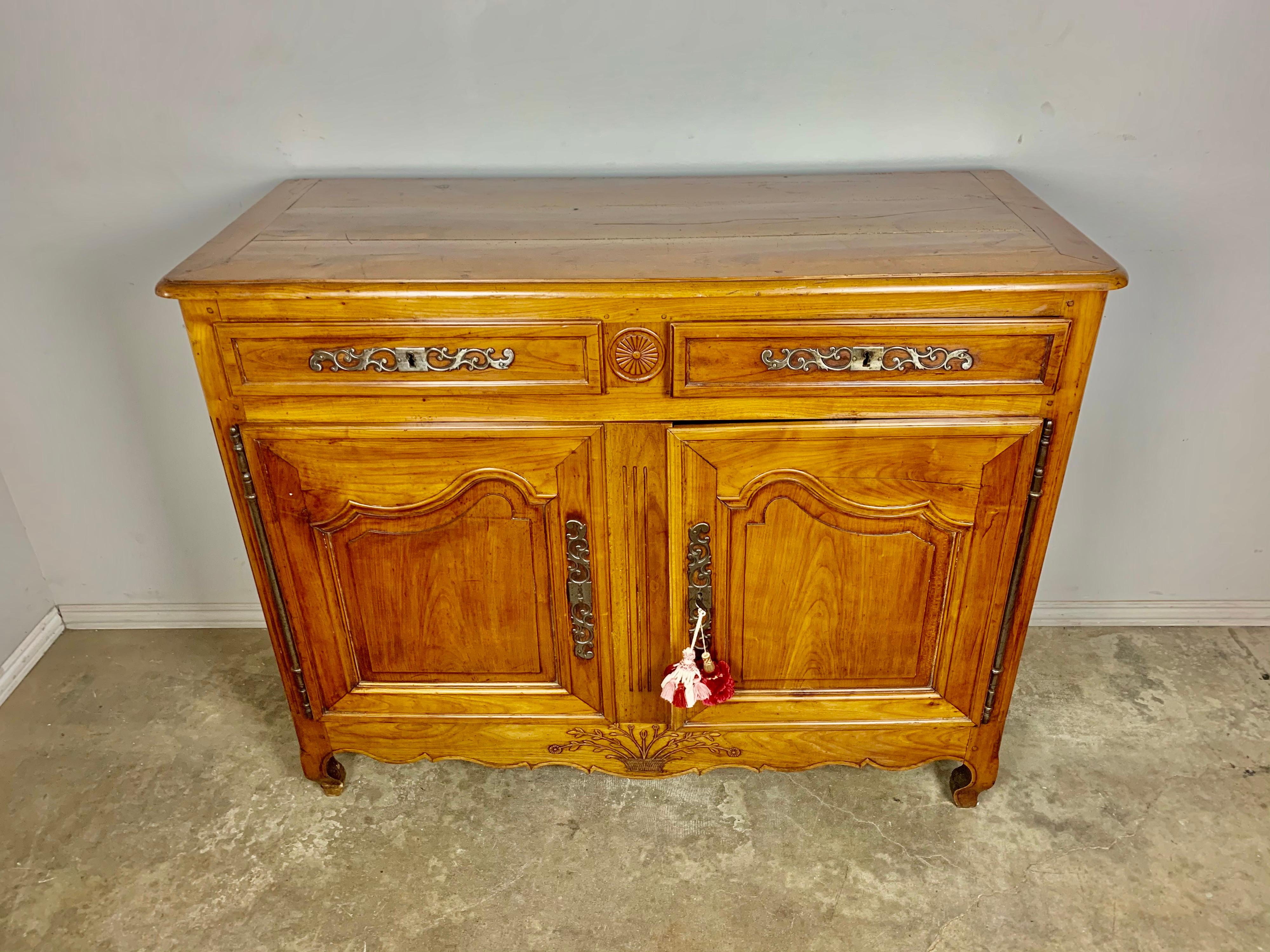 19th century French cherrywood buffet with beautiful patina. The piece has two doors and two drawers for plenty of storage. Original pewter hardware. The piece stands on four cabriole shaped legs and has a carved urn of flowers at bottom of buffet.