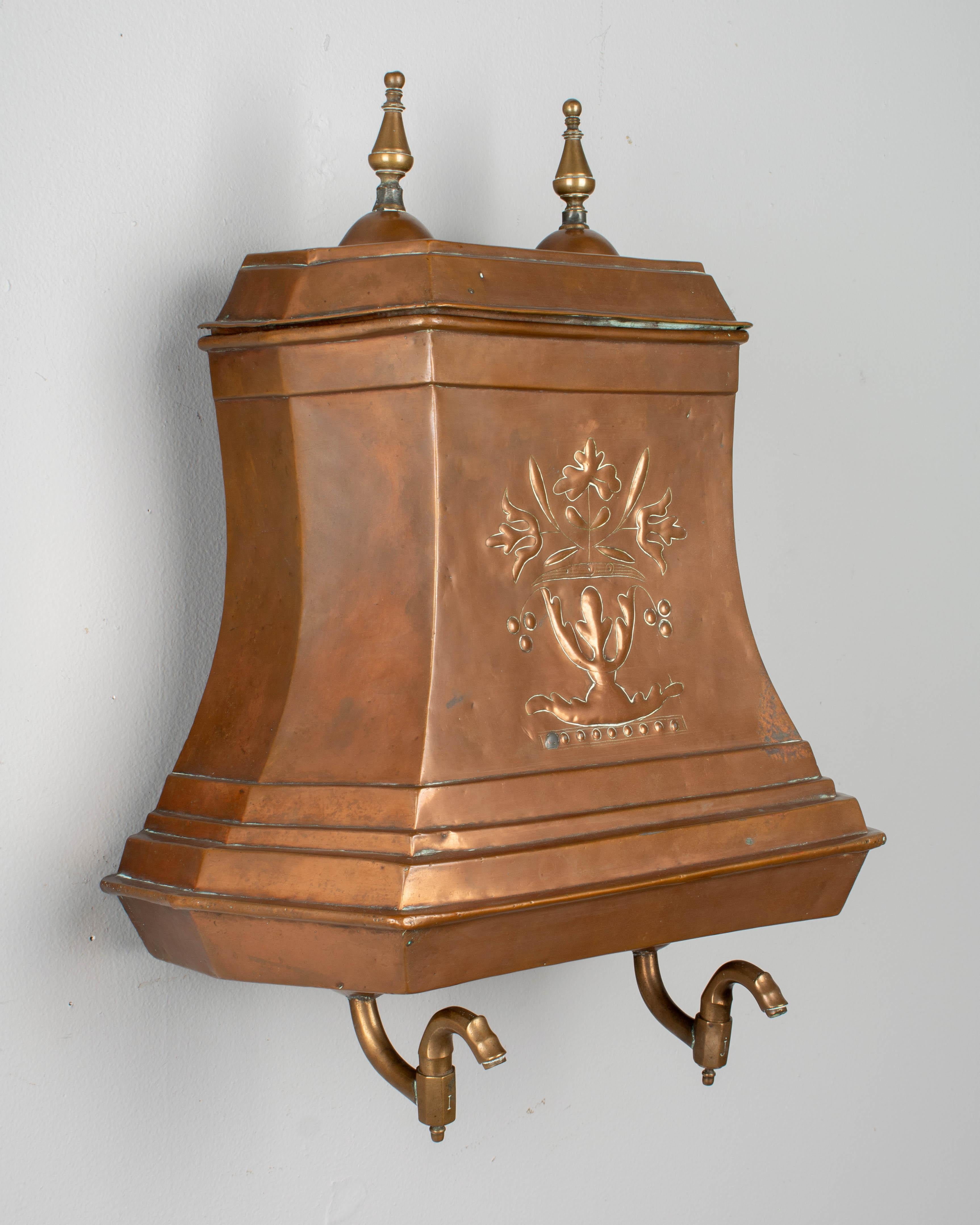 A 19th century French copper lavabo, or water tank with lovely repoussé floral decoration on the front and cast finials on the lid. The two water taps are in good condition and allow the water to empty by turning to the right or left. Lavabos were