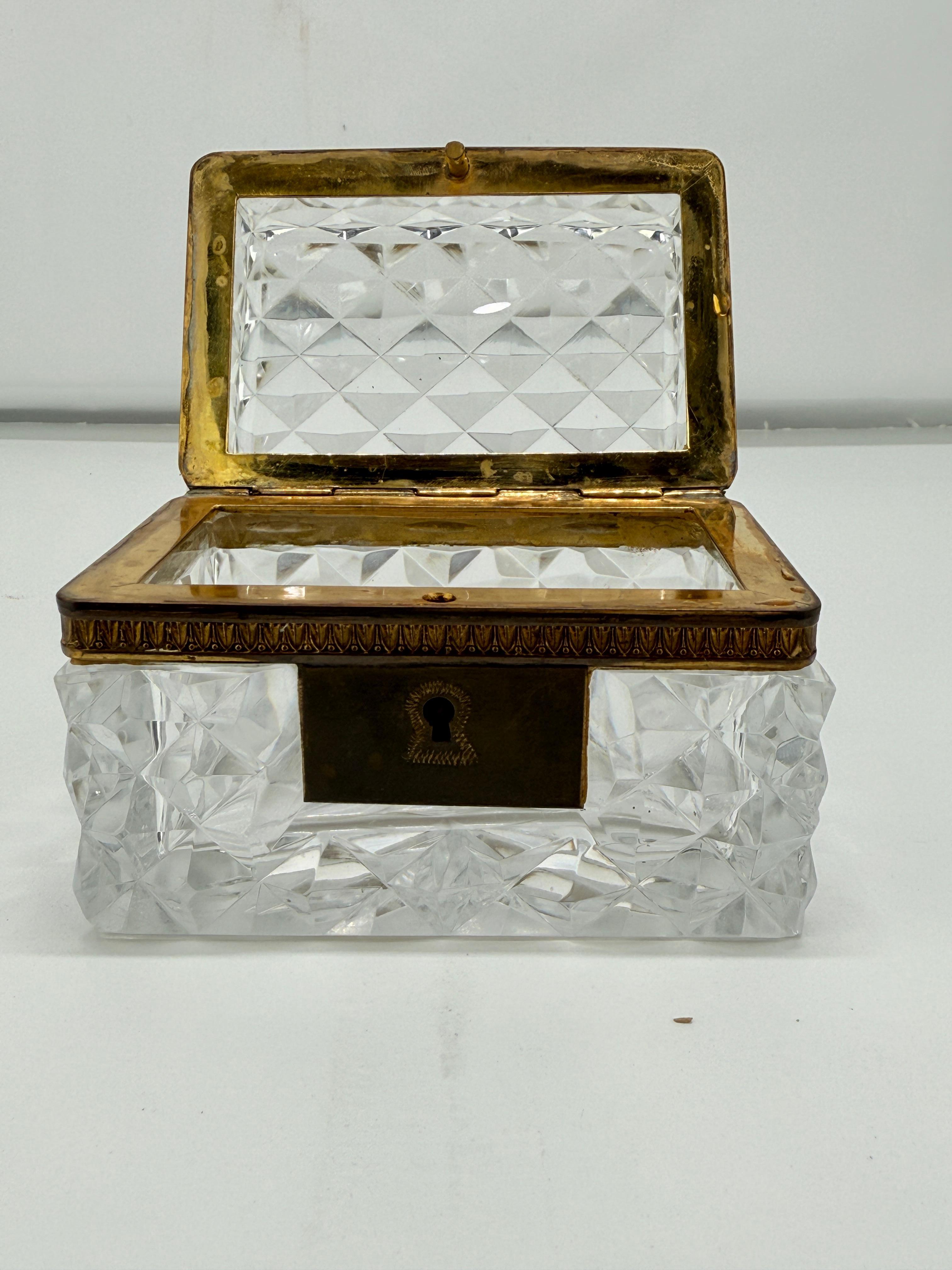 Un raffinato cofanetto francese in cristallo trasparente, risalente alla fine del XIX secolo, che si distingue per il corpo a diamante profondamente sfaccettato e il coperchio a cupola, il tutto incastonato in montature in bronzo dorato finemente