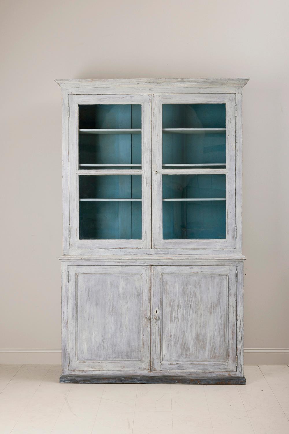 A 19th c. French bibliothèque in two parts with original glass and adjustable shelves. Found in Provence. This beautiful vitrine cabinet or bookcase is the perfect piece for almost any room. The exterior color is aged, soft gray. The interior is a