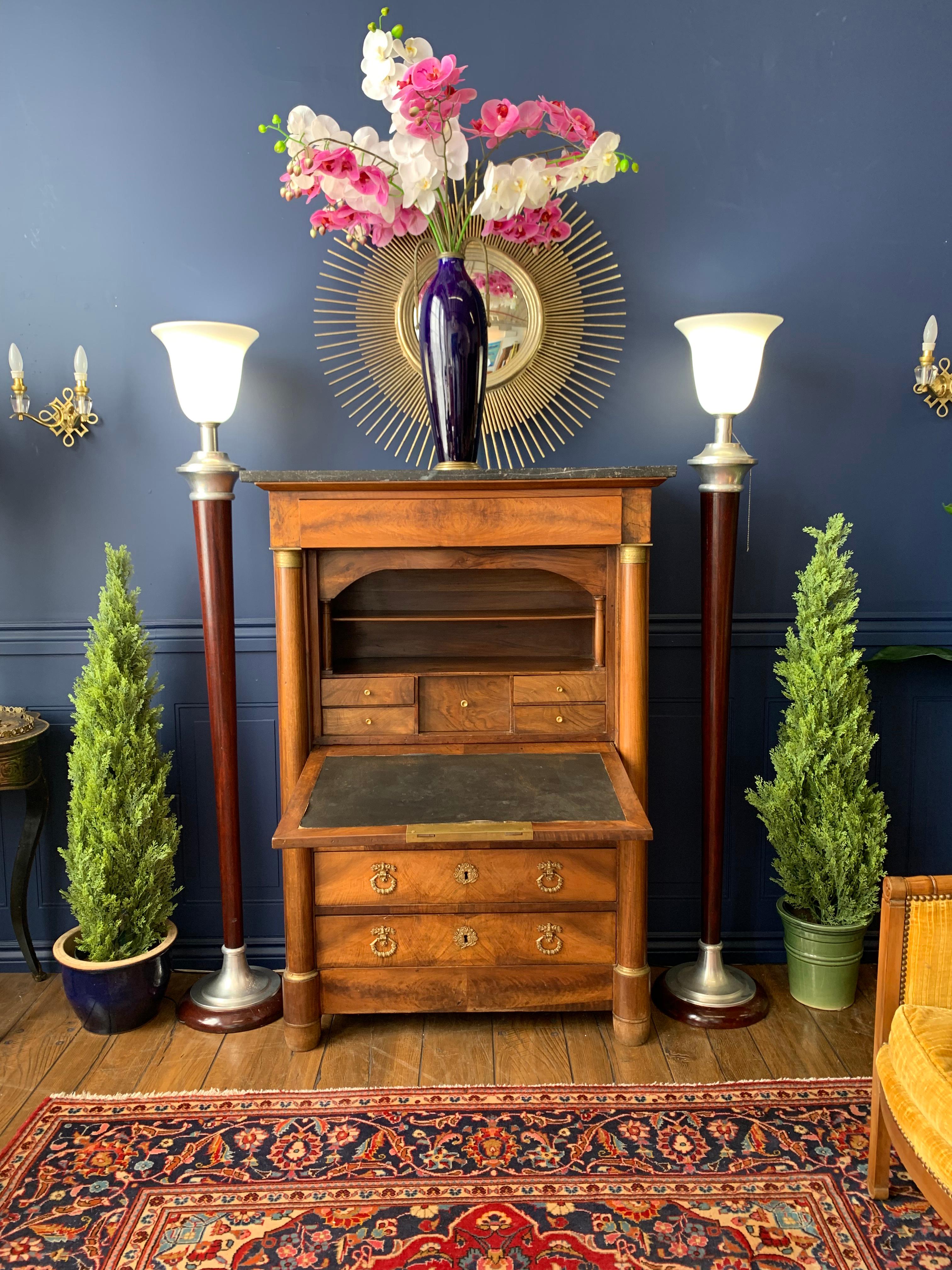 A 19th century French Empire drop front secretary with black as a marble top and side columns with bronze mounts, three drawers below and one drawer above. Double brass locking system.
The desk drops down to reveal a leather top writing surface and