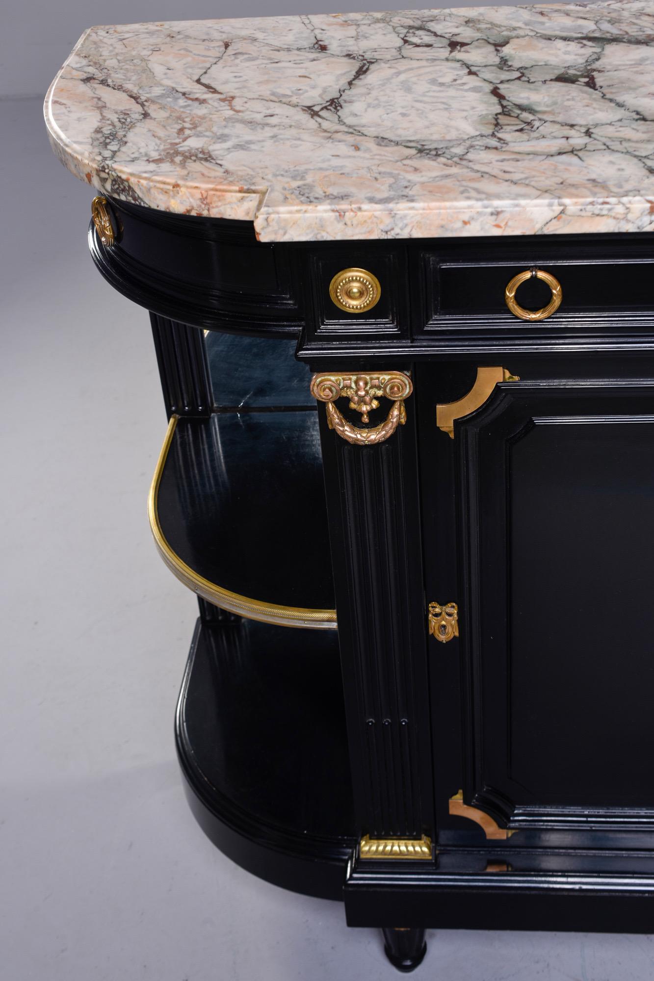 Empire style French commode has marble top with three drawers at the top, a locking center drawer and two swing out corner drawers, Circa 1860s. Open shelf compartments on the sides flank a locking center cabinet. Black finish with brass hardware