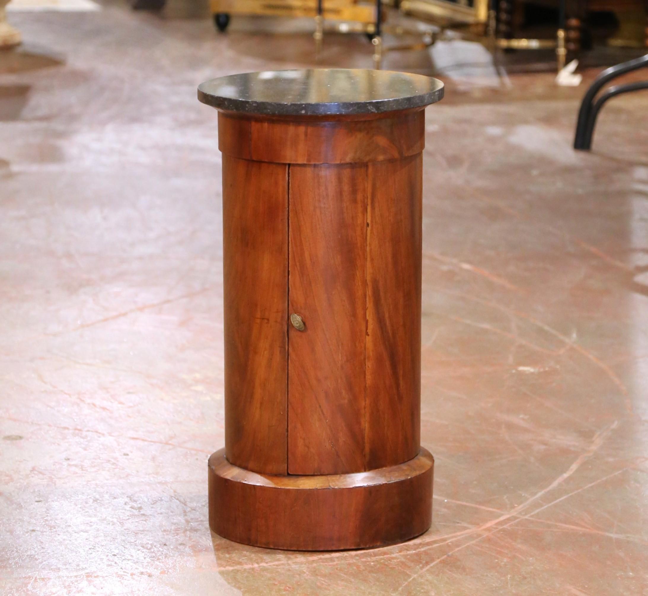 This antique French bouillotte table was crafted circa 1870 in the Empire style and features a rich walnut cylindrical body topped with a round fossil black marble surface. The marble is finely honed and subtly speckled with fossil inclusions,