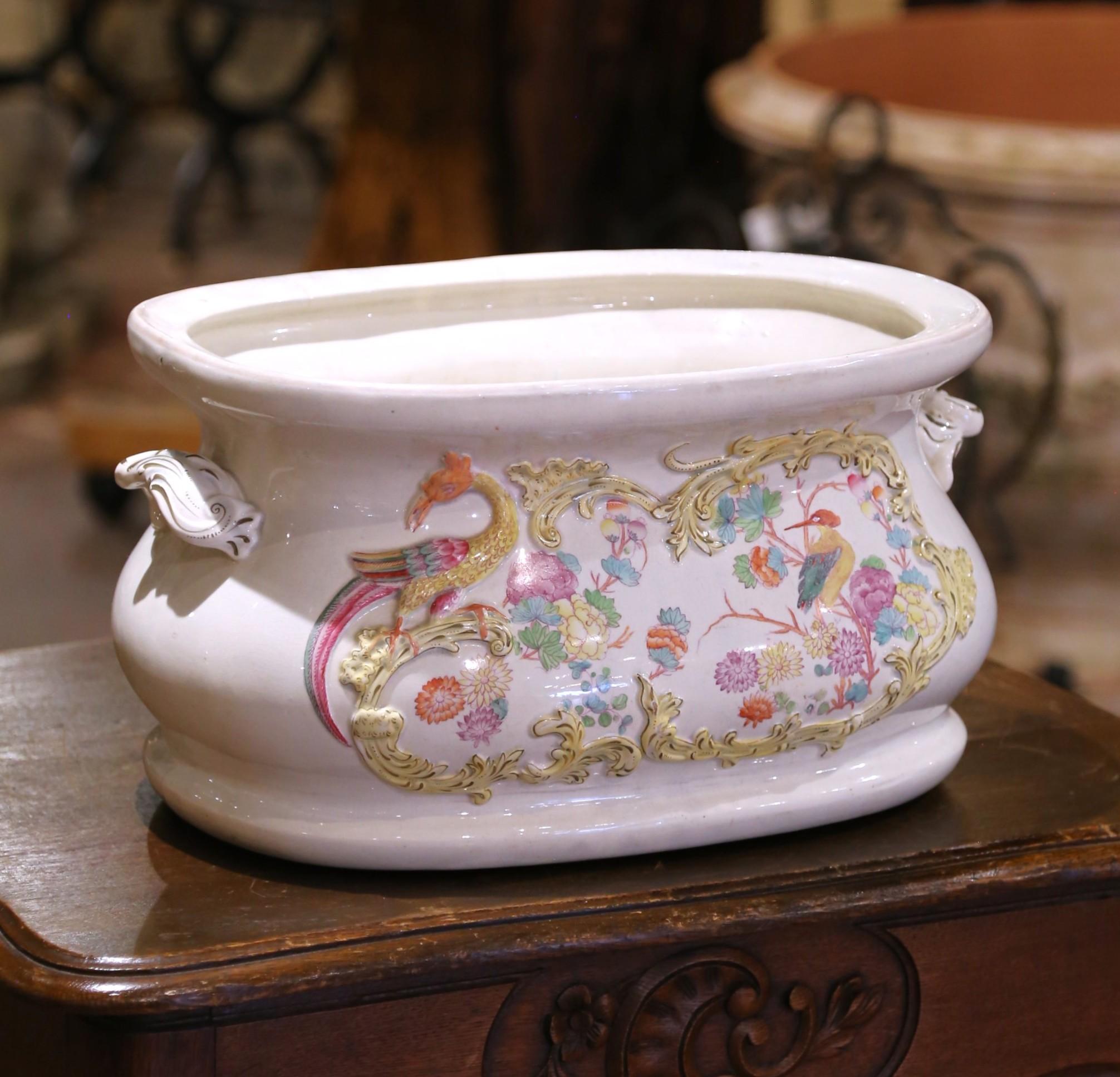 Add a touch of whimsical elegance to your space with this charming 19th-century French faience foot bath. Crafted circa 1880, the oval basin features richly molded rococo cartouches on each side, framing hand-painted chinoiserie-style scenes of