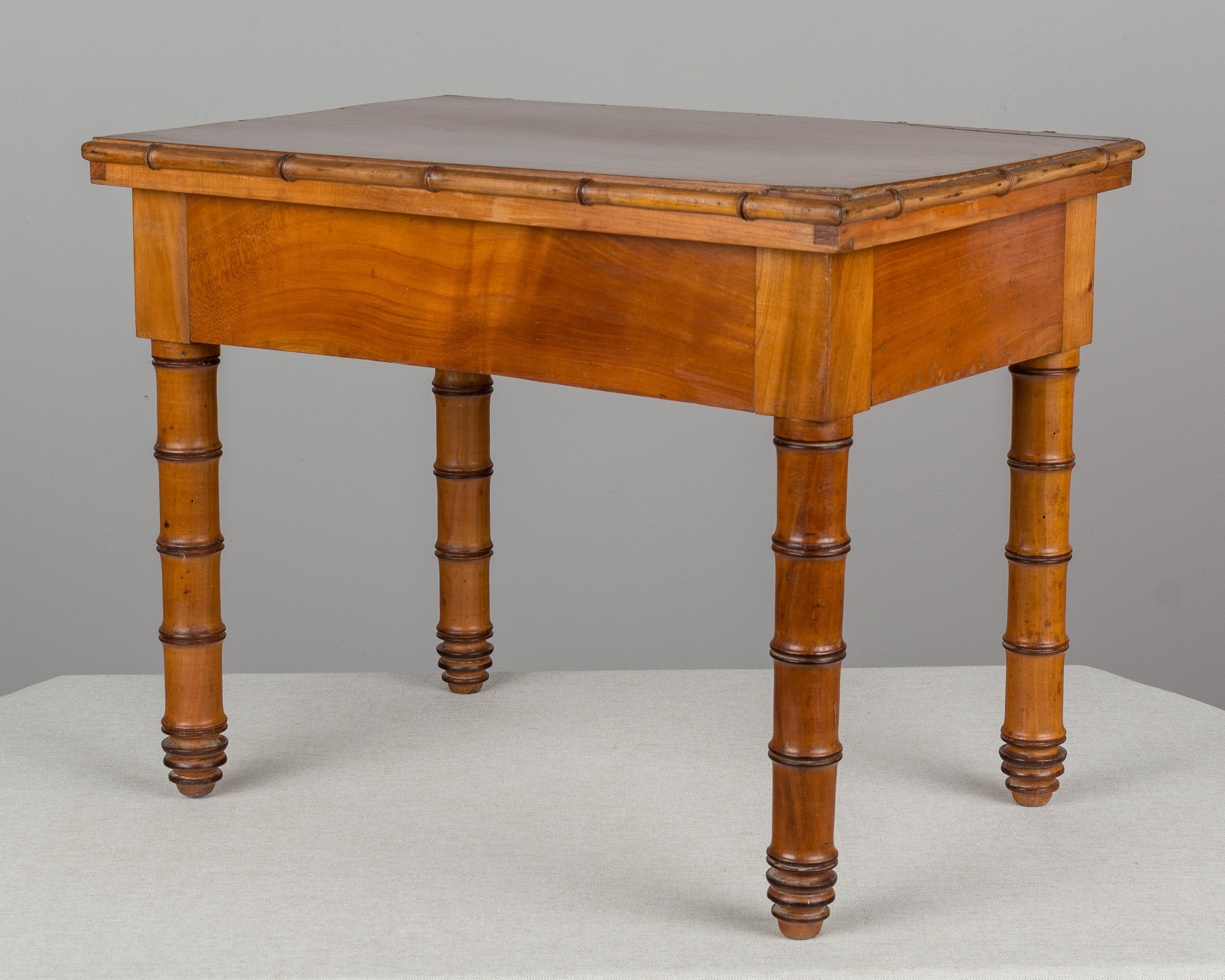 A 19th century French faux bamboo small side table made of solid cherry. Top opens to reveal a porcelain bidet inside a zinc liner.
