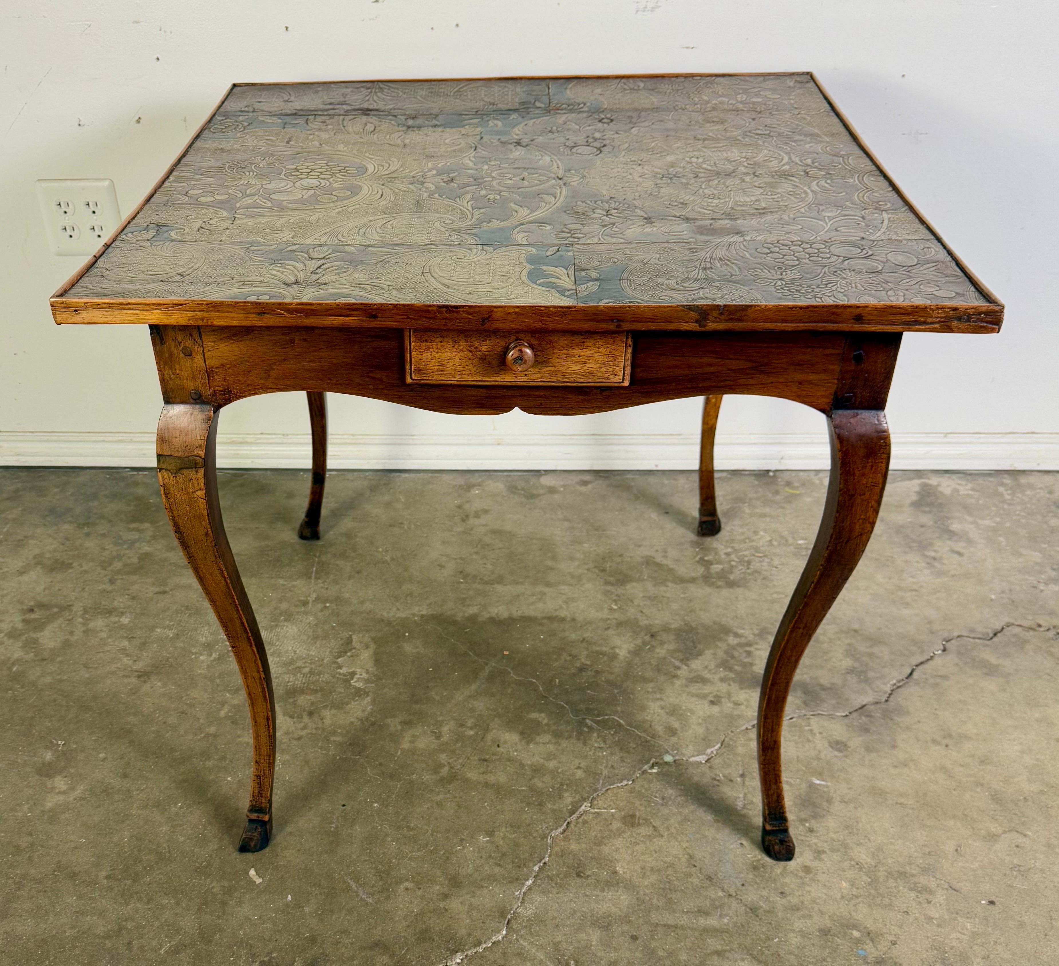 19th C. French Provincial wooden game table with a square top and four drawers.  It features an embossed leather top that has been constructed from 19th C. Spanish embossed leather.  The four drawers each have a single knob.  The legs are cabriole