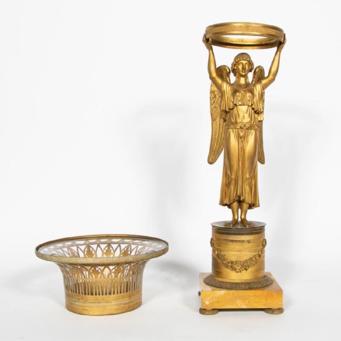 First quarter 19th century, in the manner of Pierre-Philippe Thomire (French, 1751–1843), gilt bronze and marble, figural basket, possibly Nike, holding aloft a flared, reticulated basket with glass liner, on a drum plinth with floral garlands with