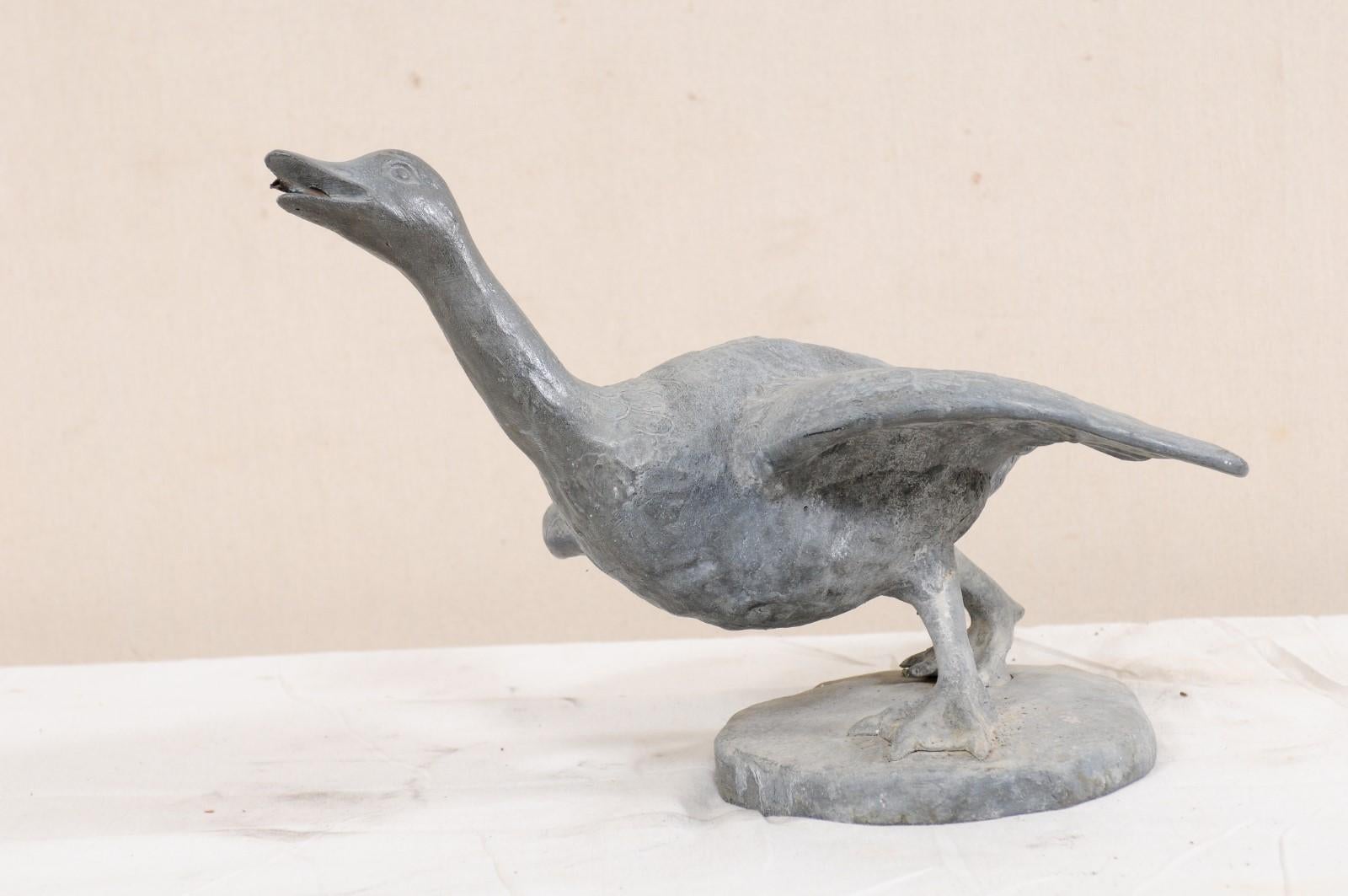 A French goose garden statue (or water spout for fountain) from the 19th century. This antique statue from France, created in lead, features a very expressive goose- in walking position with head inquisitively upward, and wings lowered at sides.